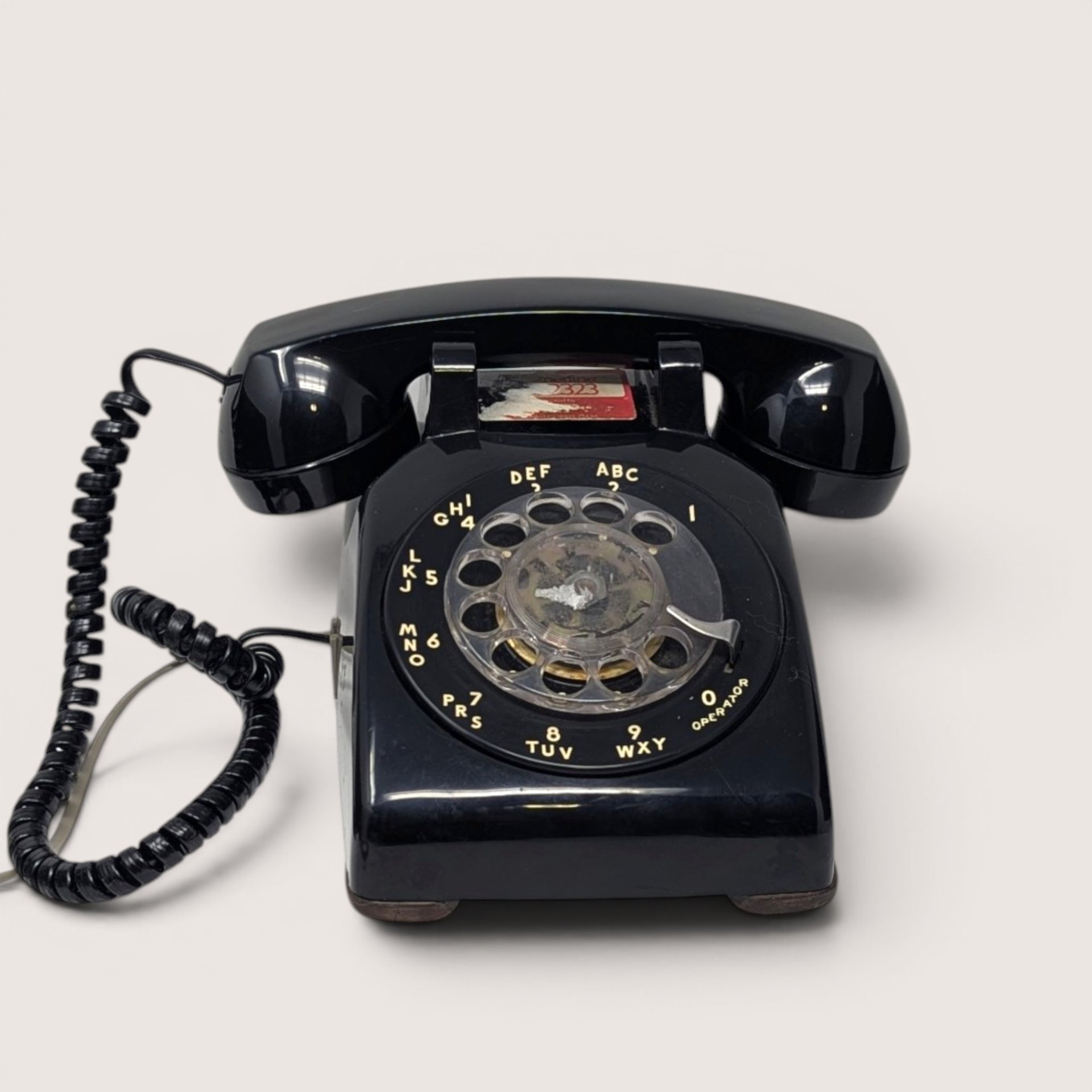 1984 AT&T vintage black rotary desk phone with a circular dial and coiled cord.