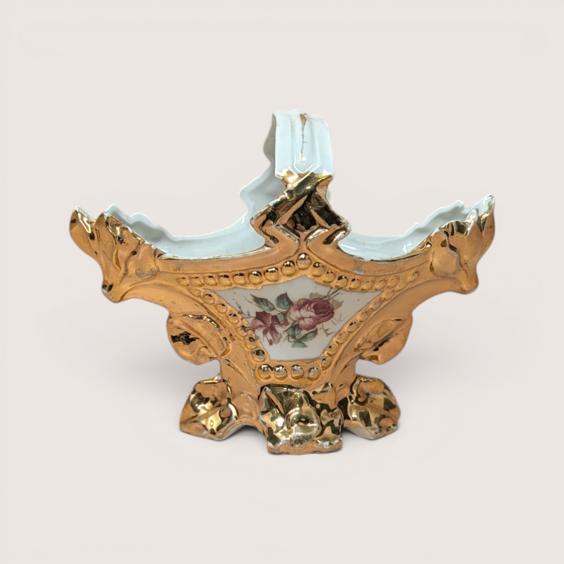 Vintage porcelain decorative basket with a floral rose painting surrounded by heavy gold gilt scrollwork and handle.