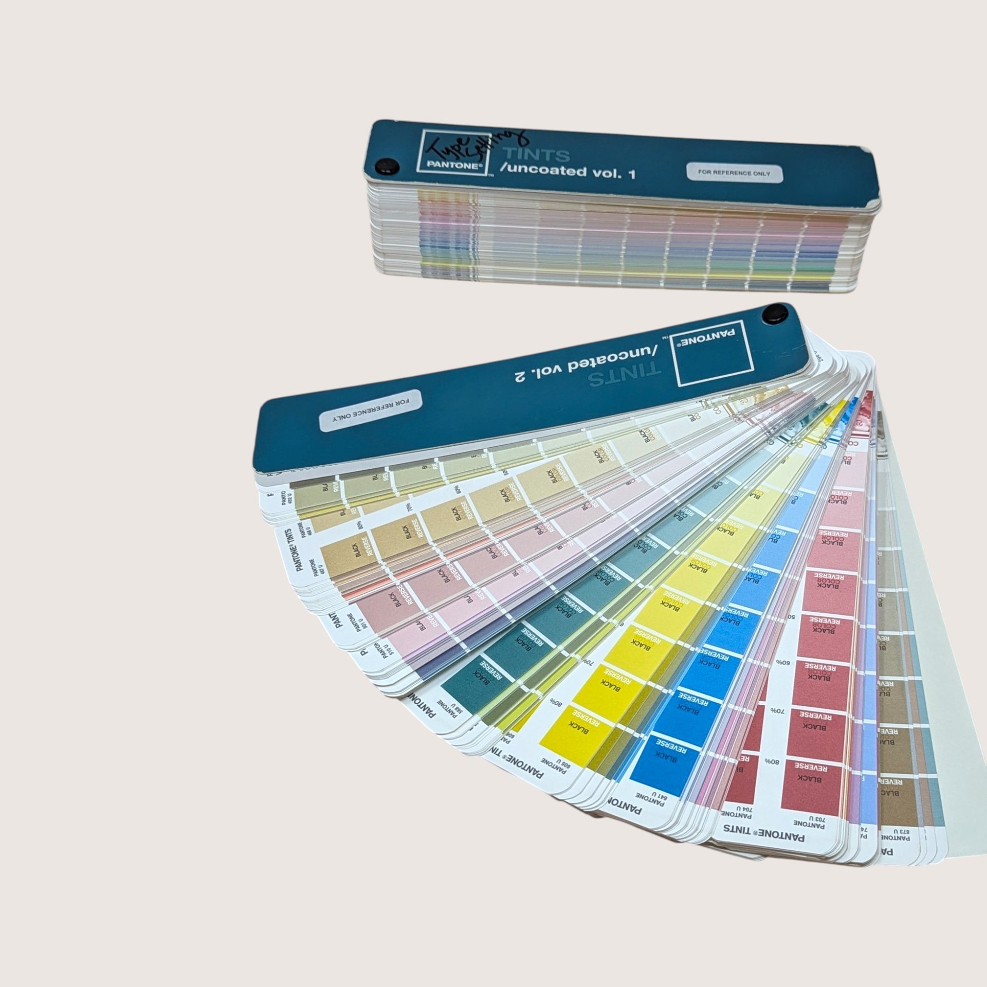 Vintage Pantone Tints Uncoated Volumes 1 and 2 color swatch fan decks fanned open showing rainbow color chips.