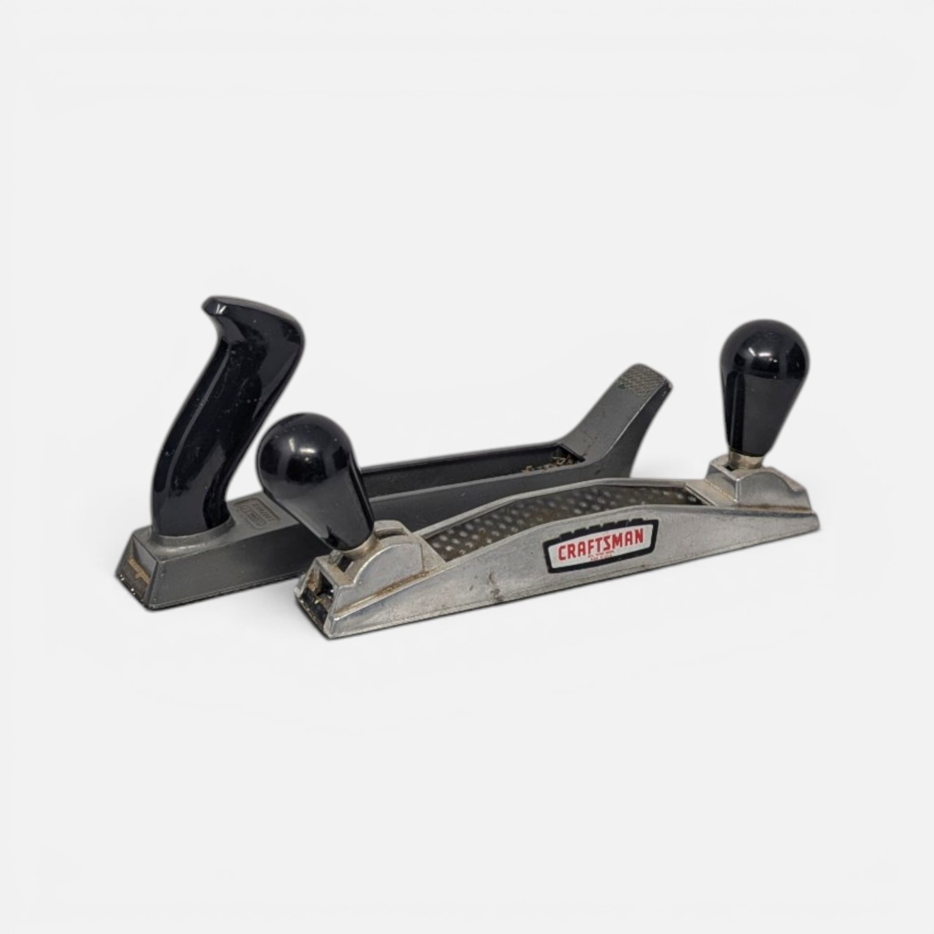 Vintage pair of Stanley and Craftsman wood planers with metal bodies and black handles.