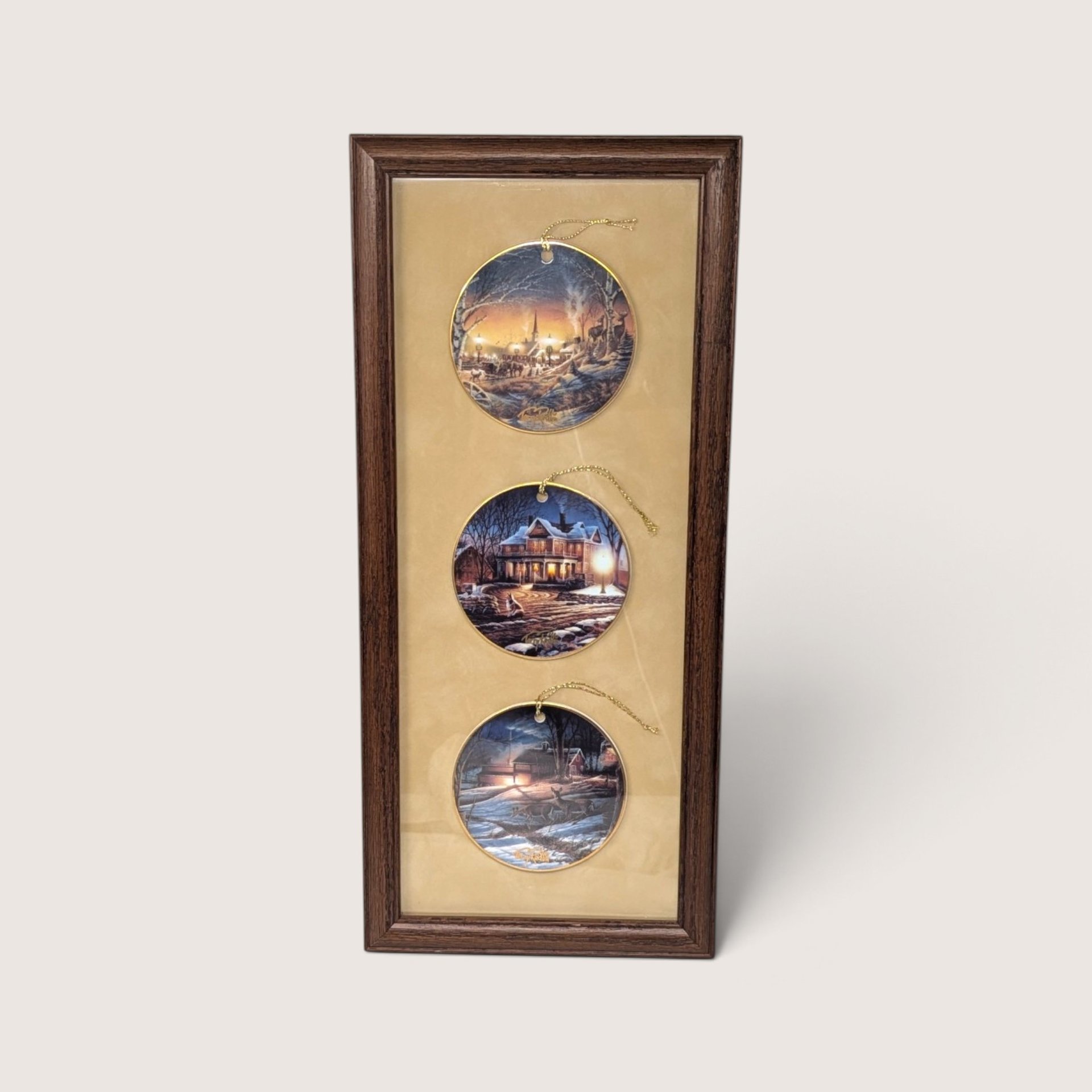 Vintage 1990s Terry Redlin set of three porcelain holiday ornaments featuring winter landscapes, professionally mounted in a wooden frame.