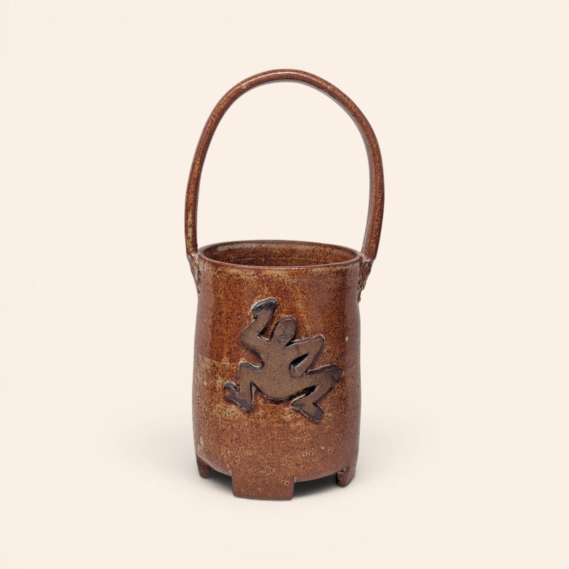 Vintage handmade stoneware pottery basket with a brown speckled glaze and an applied frog figure on the side.