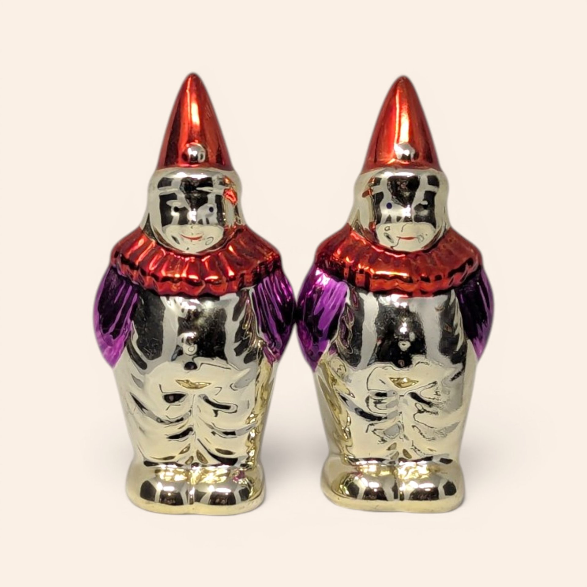 Pair of vintage metallic clown salt and pepper shakers with red hats and purple sleeves.