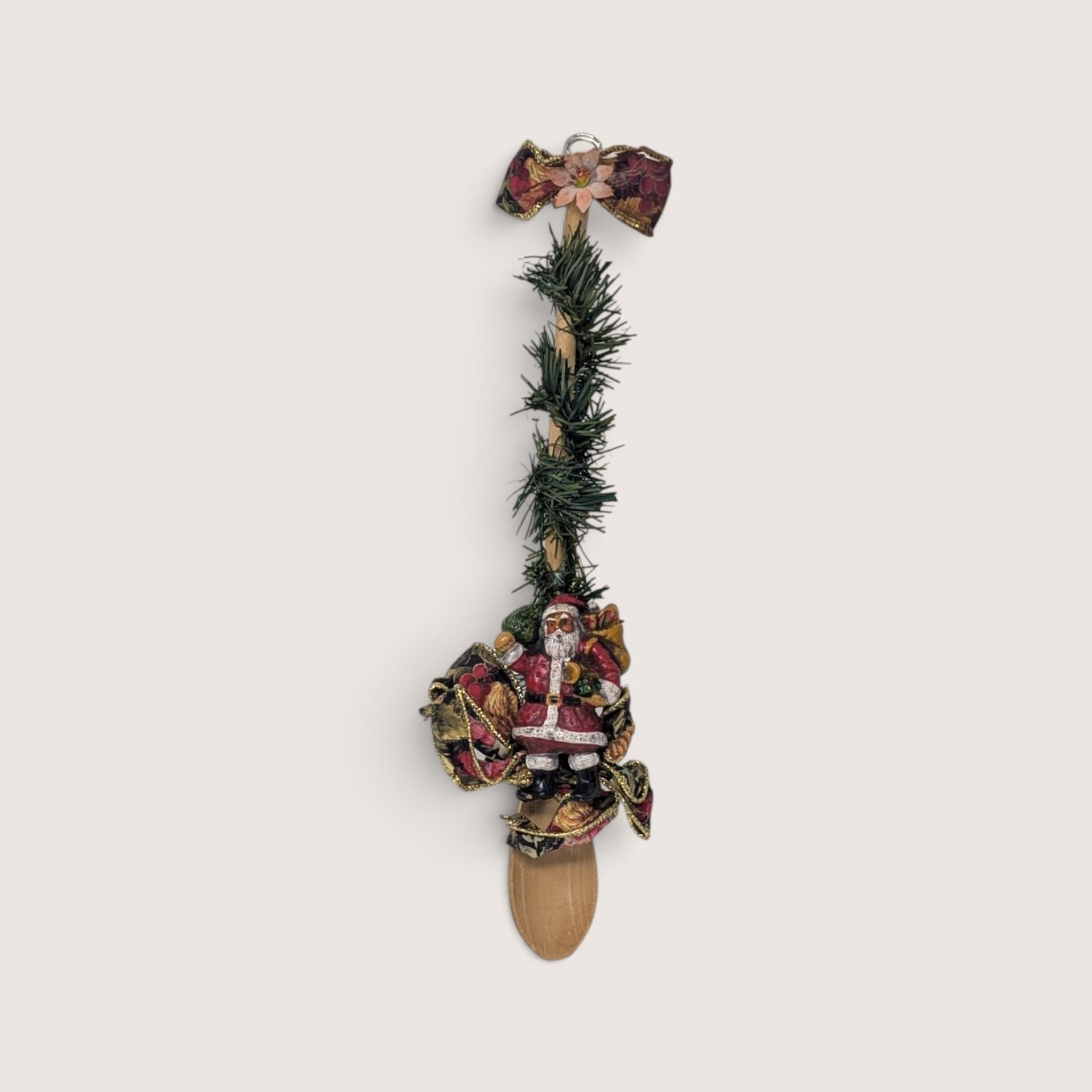 Vintage handmade wooden spoon decorated with faux pine garland and a Santa figure for Christmas wall hanging