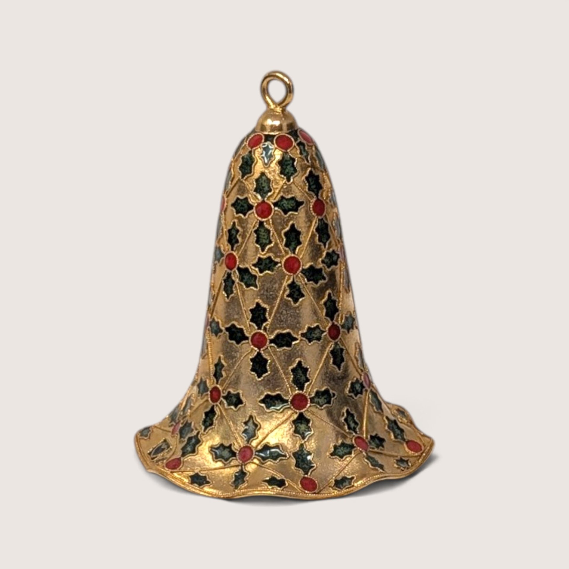 Close-up detail of vintage enamel and metal bell ornament showing green and red holly design.