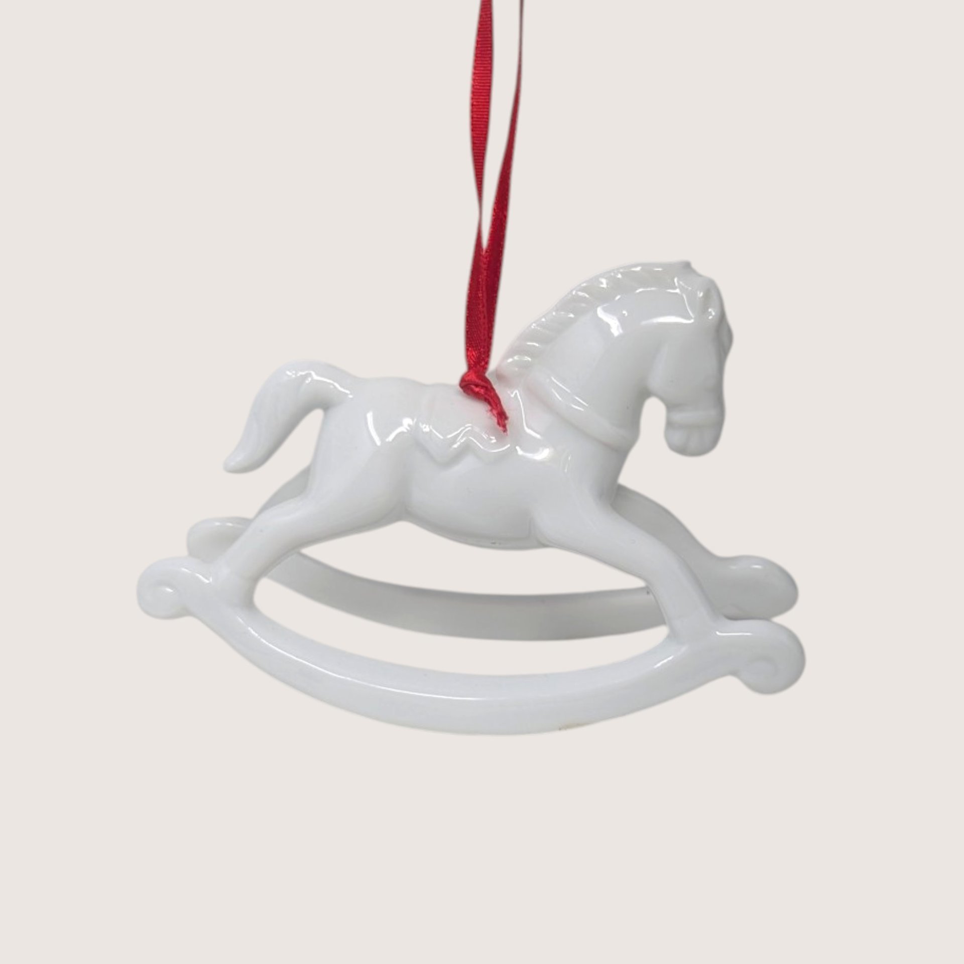 Vintage Dept 56 glossy white porcelain rocking horse Christmas tree ornament with a red ribbon.