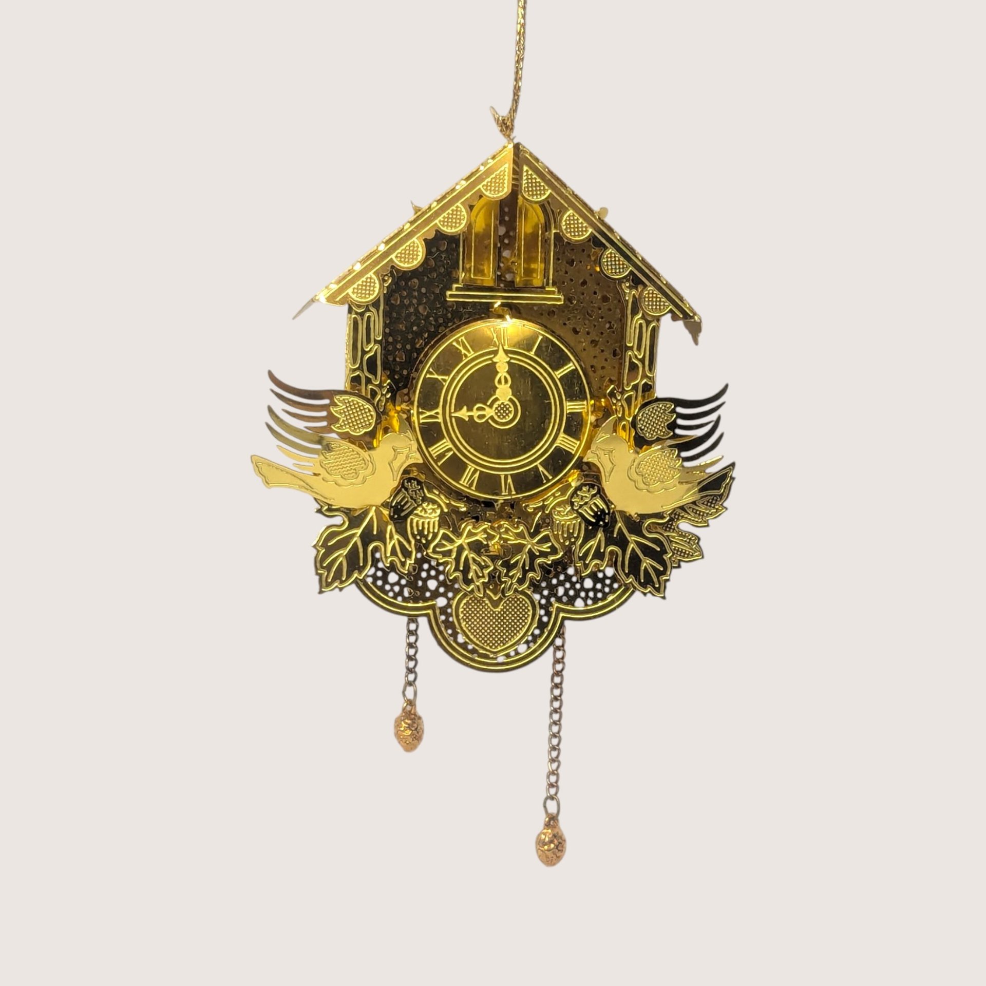 Vintage gold-tone laser-cut metal cuckoo clock ornament featuring hanging chains, dimensional birds, and a slot for a tree light.