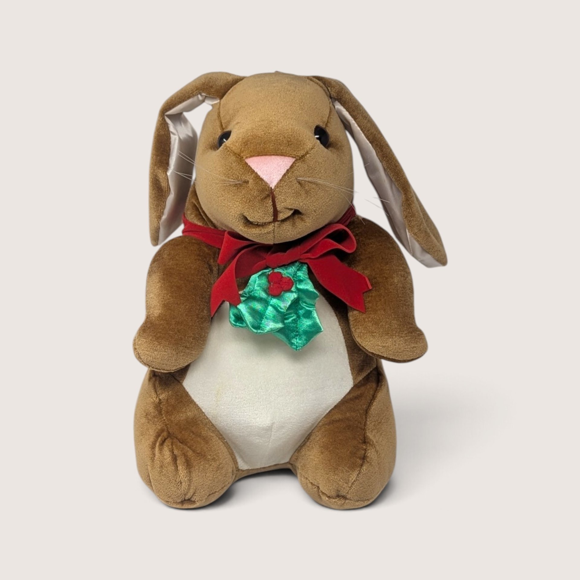 Vintage 1980s plush brown bunny rabbit wearing a festive red velvet bow and green holly accent.