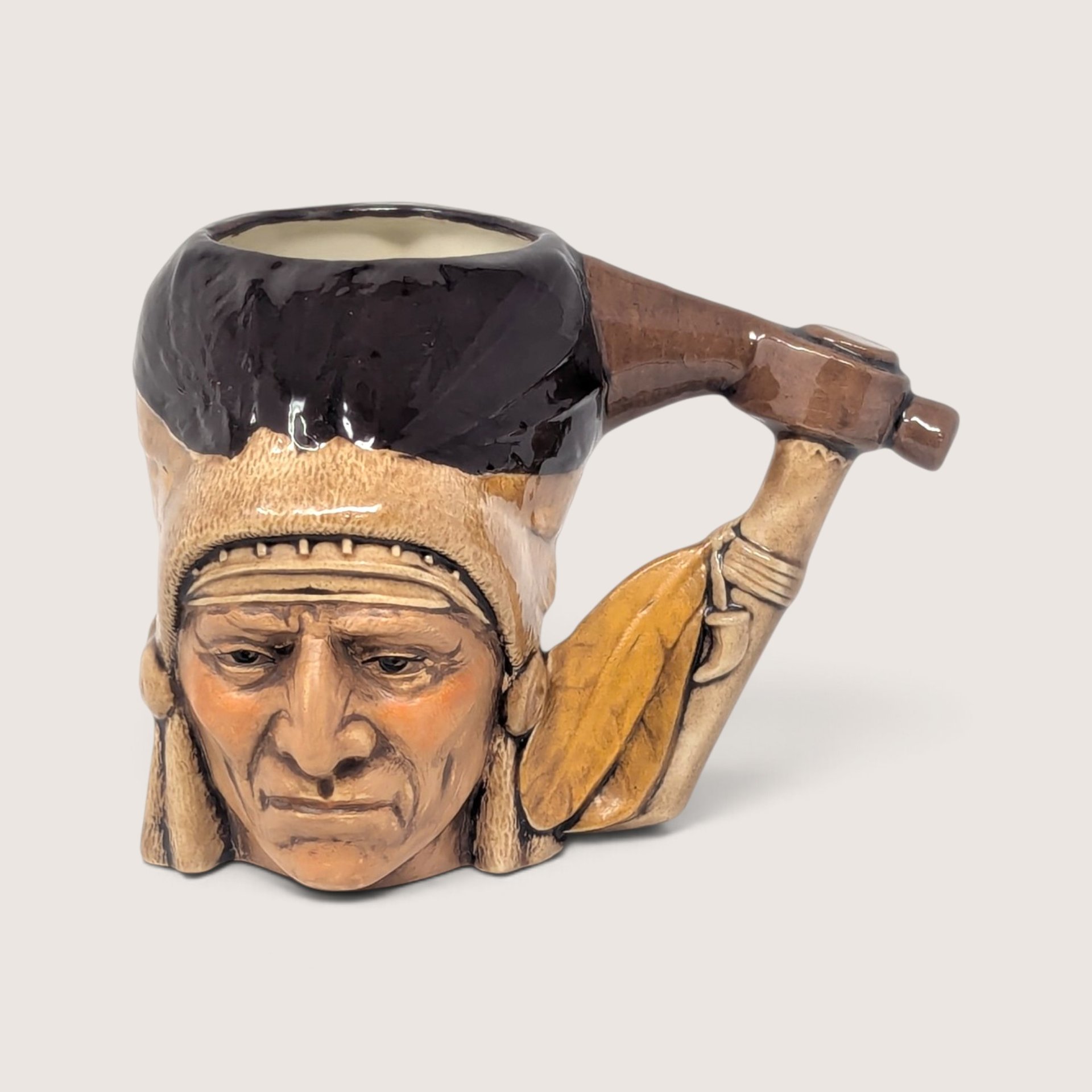 Vintage hand-painted ceramic character mug depicting a Native American chief with a tomahawk handle and feathered headdress design.