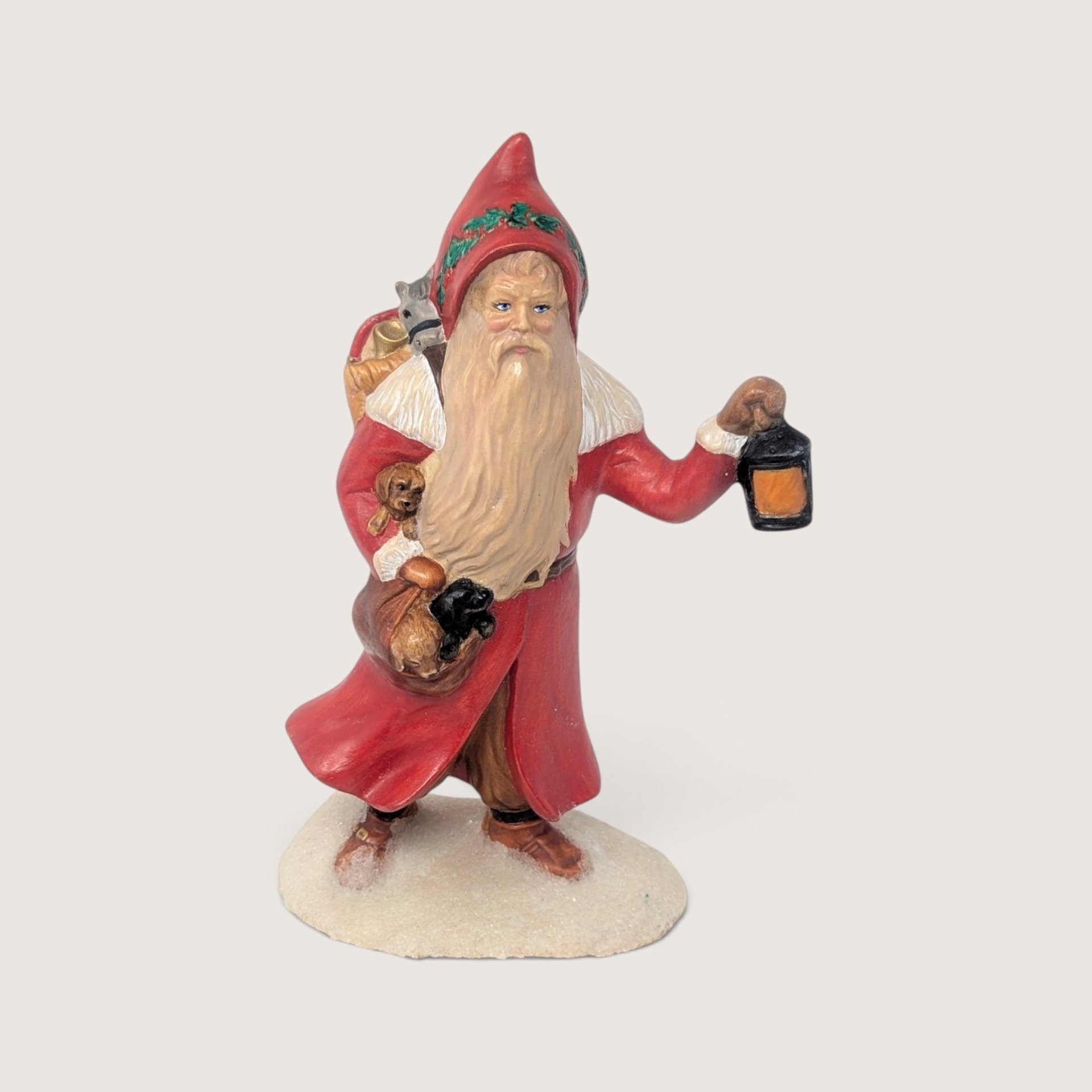 Vintage hand-painted ceramic Santa figurine carrying puppies and a lantern on a snowy base.