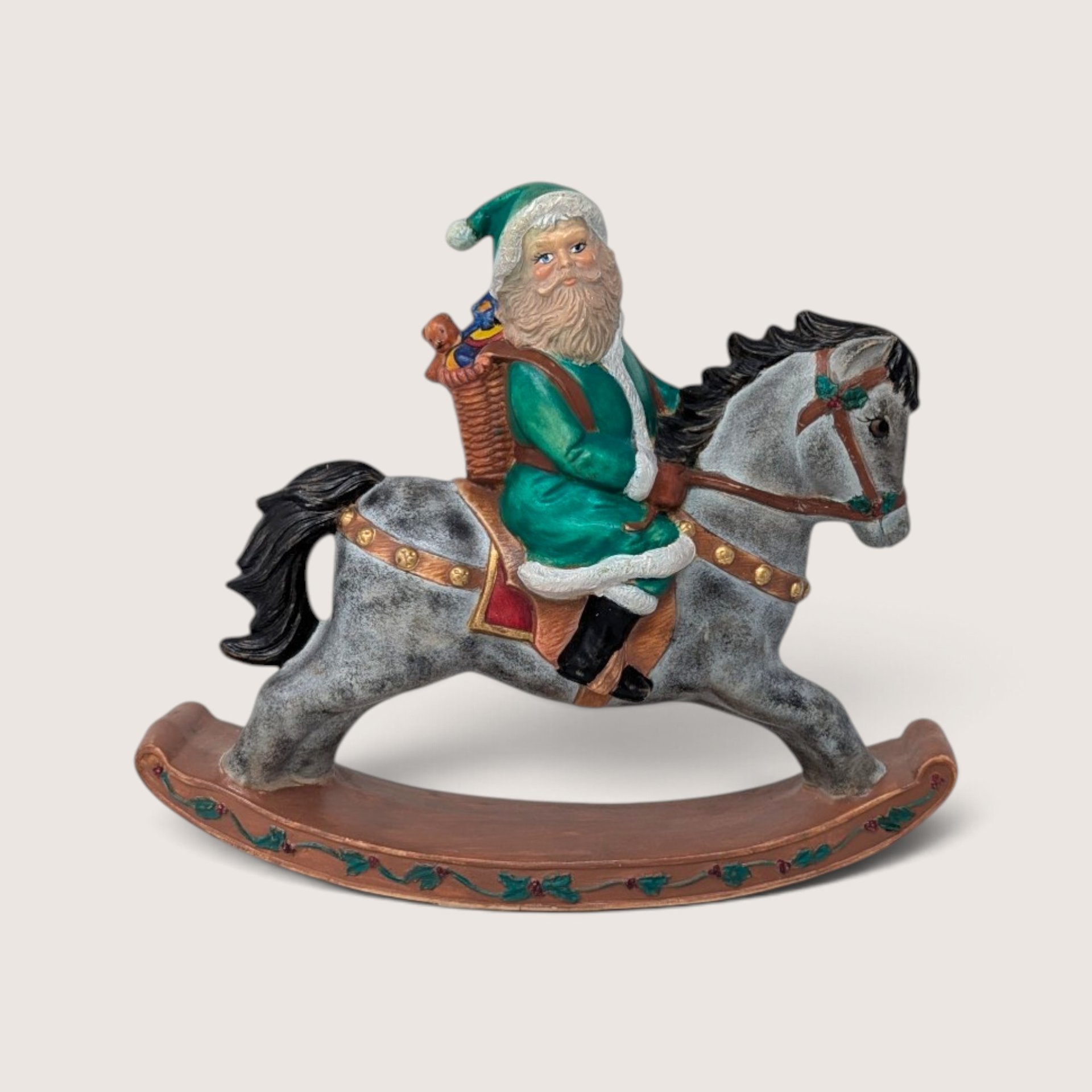 Vintage hand-painted ceramic old world Santa figurine riding a dapple-grey rocking horse in a green suit.