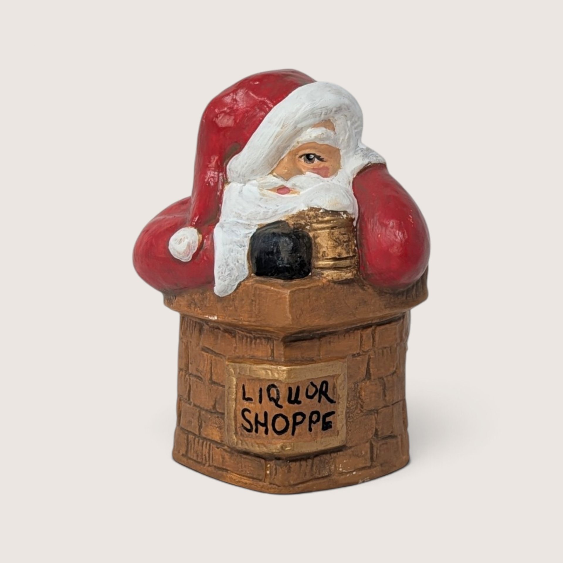 Vintage hand-painted ceramic Santa figurine sliding down a brick chimney marked Liquor Shoppe with a bag of coal.