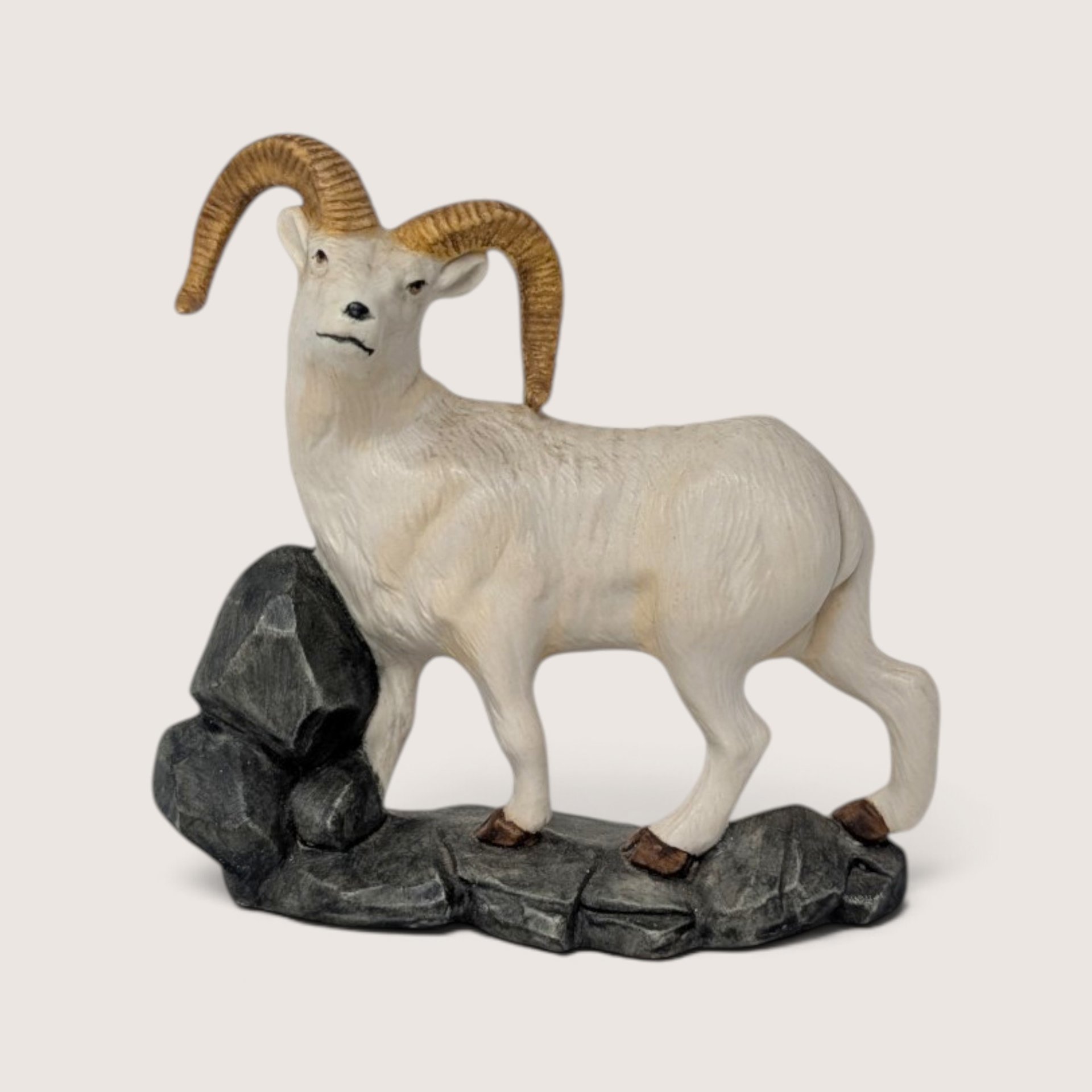 Vintage hand-painted ceramic bighorn sheep ram figurine standing on a rocky grey base.