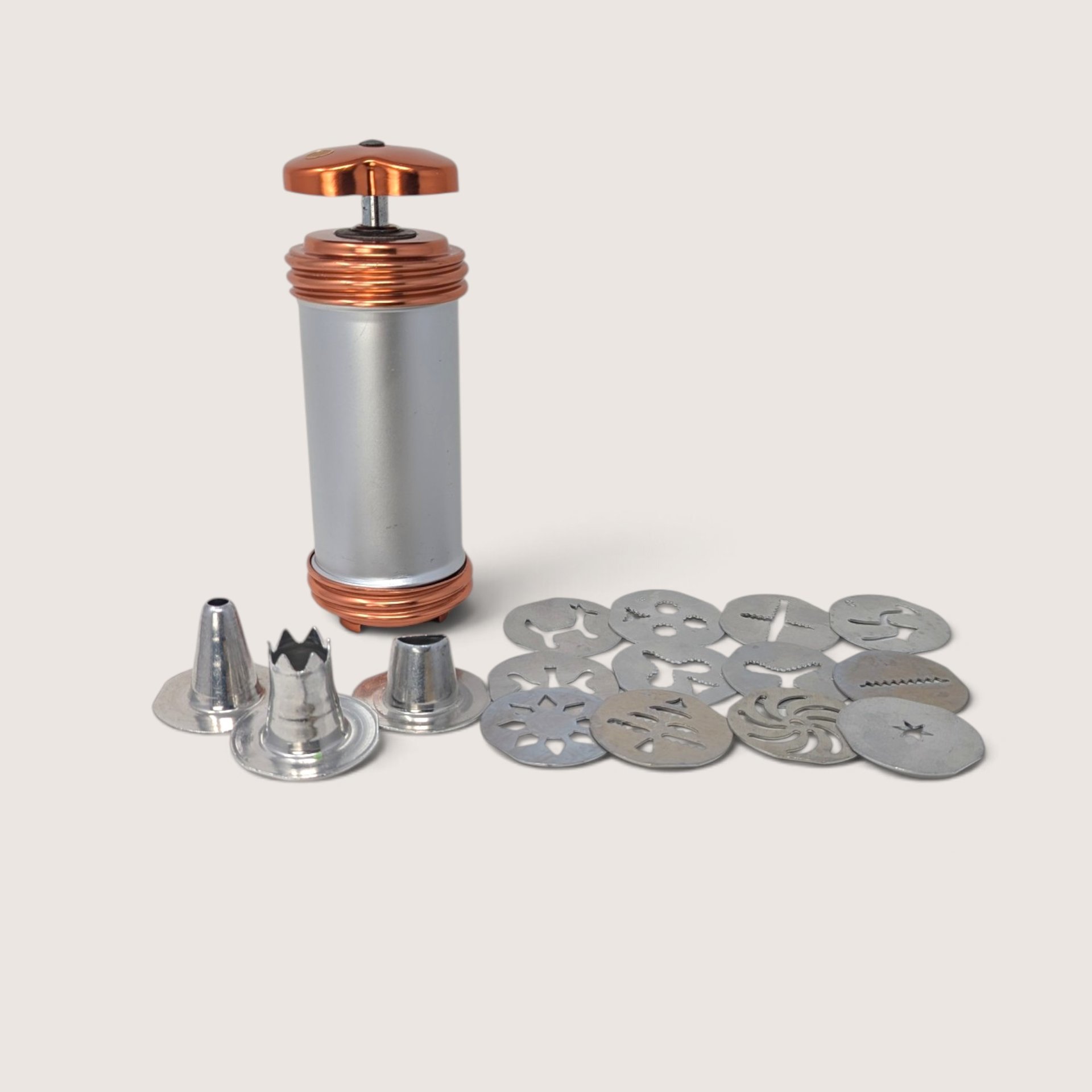 Vintage Mirro aluminum cookie press with copper-tone accents, 12 pattern disks, and 3 icing tips.