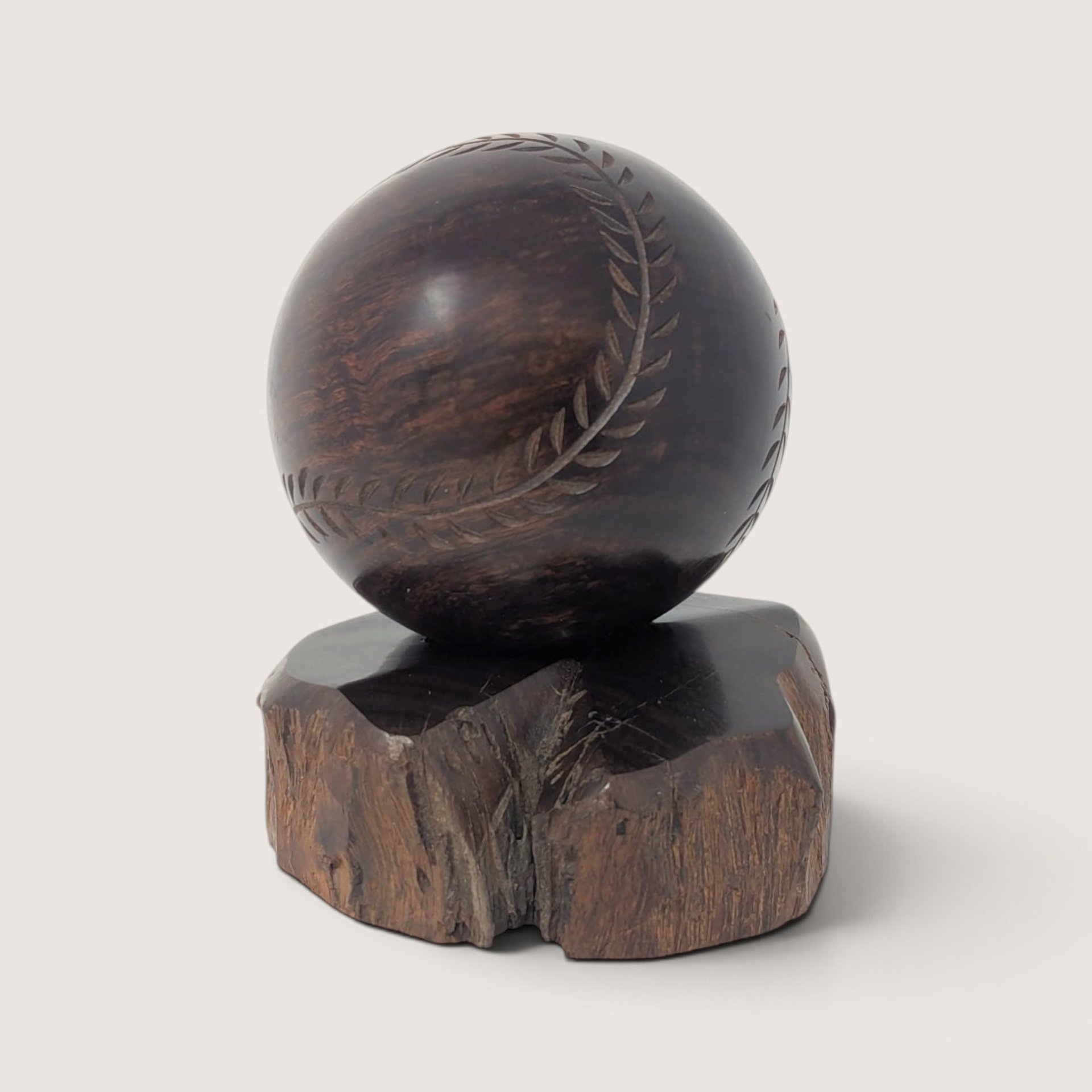 Vintage hand-carved wooden baseball display figurine resting on a natural wood base.