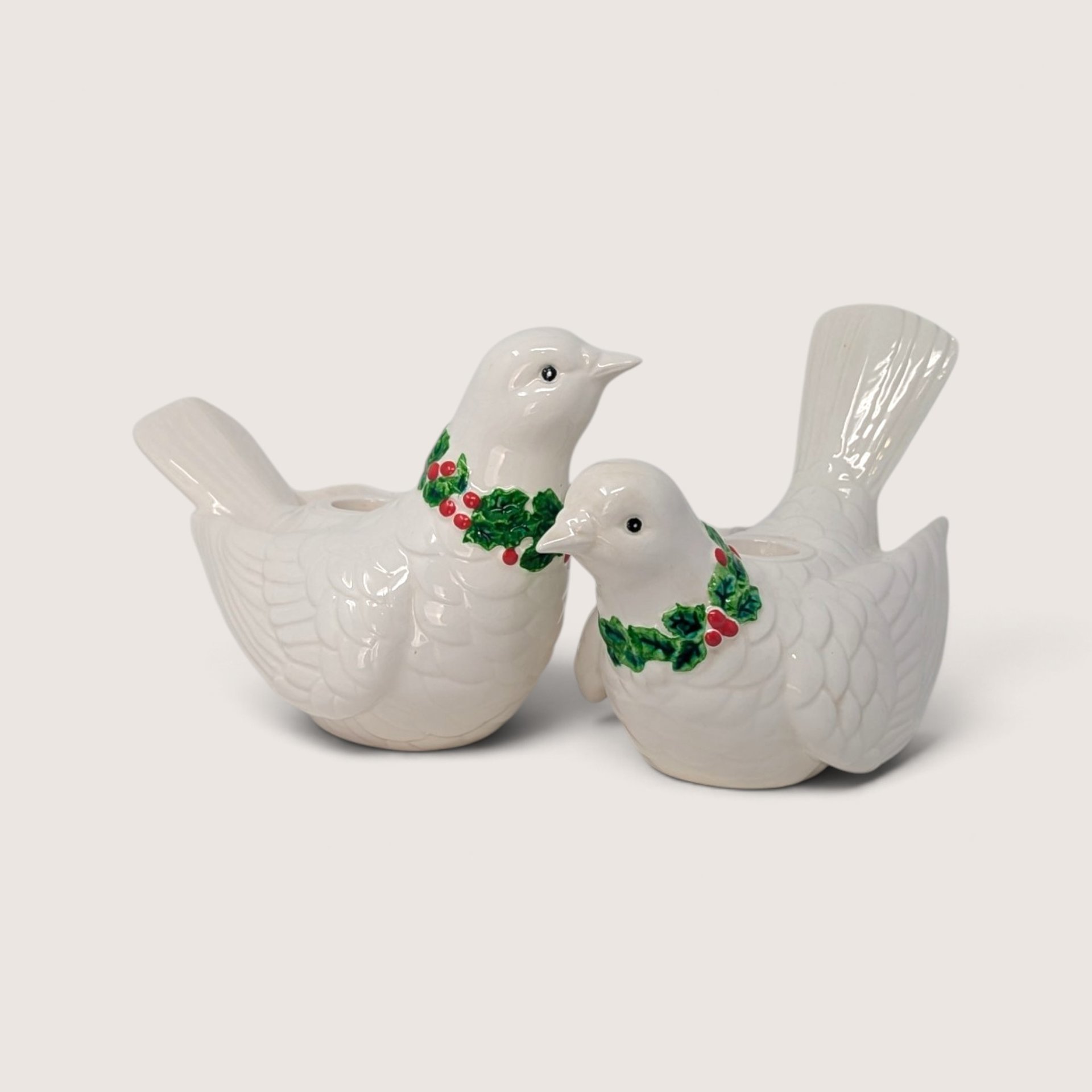 Pair of vintage Fitz and Floyd white ceramic dove candle holders with green holly wreaths and red berries.