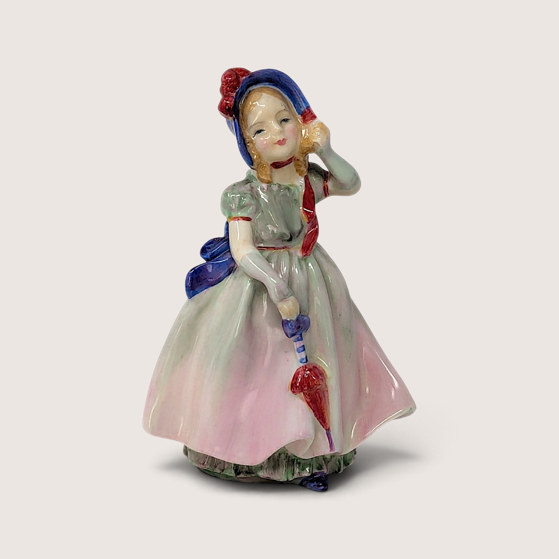 Vintage Royal Doulton Babie porcelain figurine of a young girl wearing a blue bonnet and holding a parasol.
