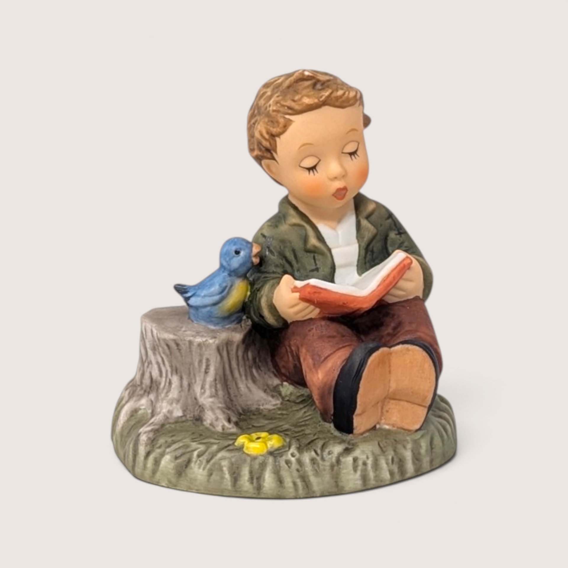 Vintage 1999 Goebel M.I. Hummel Singing Lesson porcelain figurine of a boy reading to a bird by a tree stump.