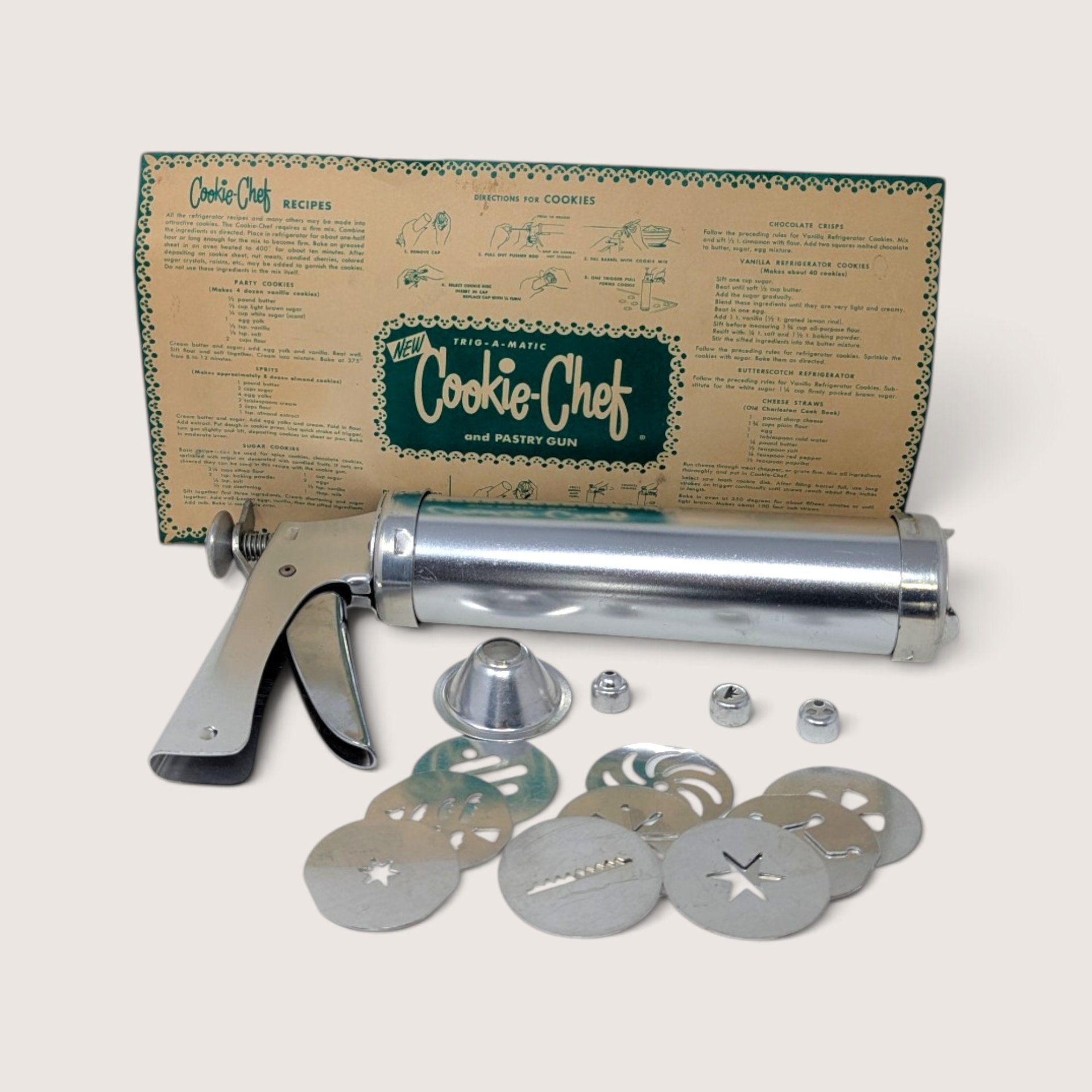 Vintage Trig-A-Matic Cookie-Chef and pastry gun with metal disks, tips, and original box.