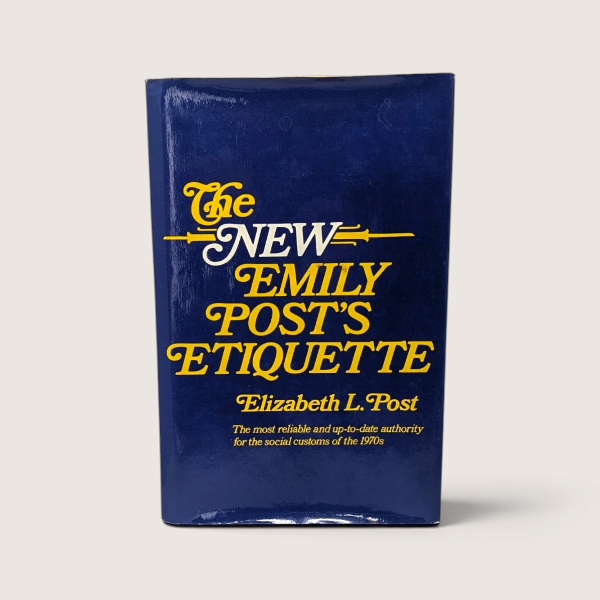 Vintage 1975 hardcover copy of The New Emily Post's Etiquette by Elizabeth L. Post with blue and yellow dust jacket.