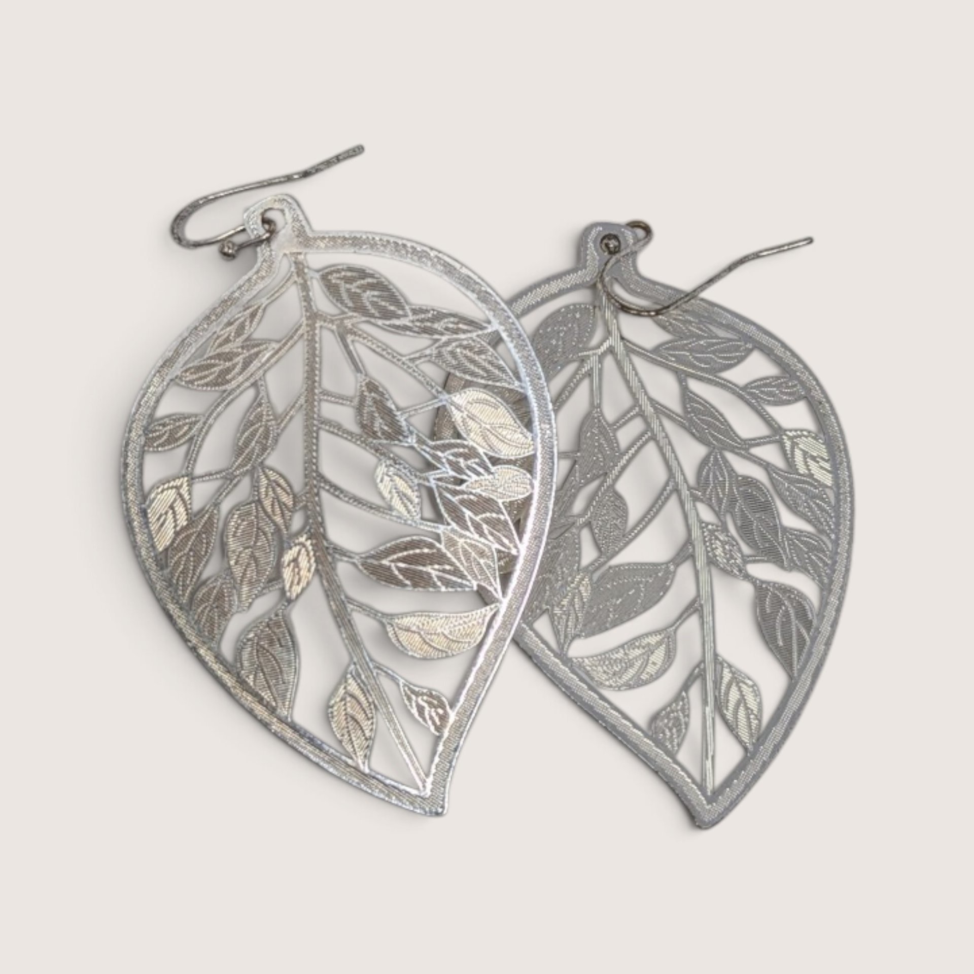 Vintage JC Penney silver-tone cutout leaf dangle earrings with intricate filigree texture.