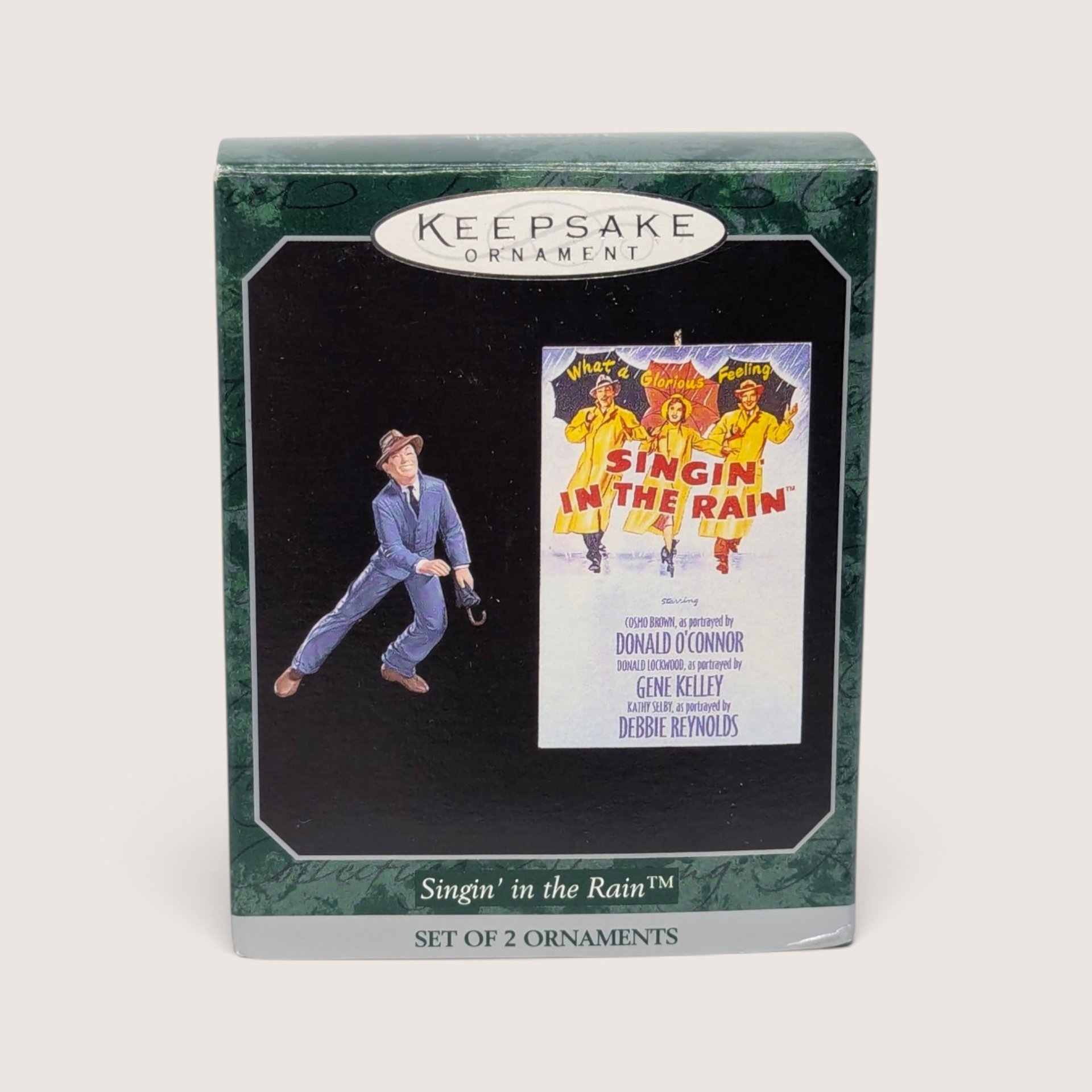 Vintage Hallmark Keepsake Singin' in the Rain Christmas ornament set featuring a figurine of Gene Kelly dancing with an umbrella and a miniature movie poster replica.