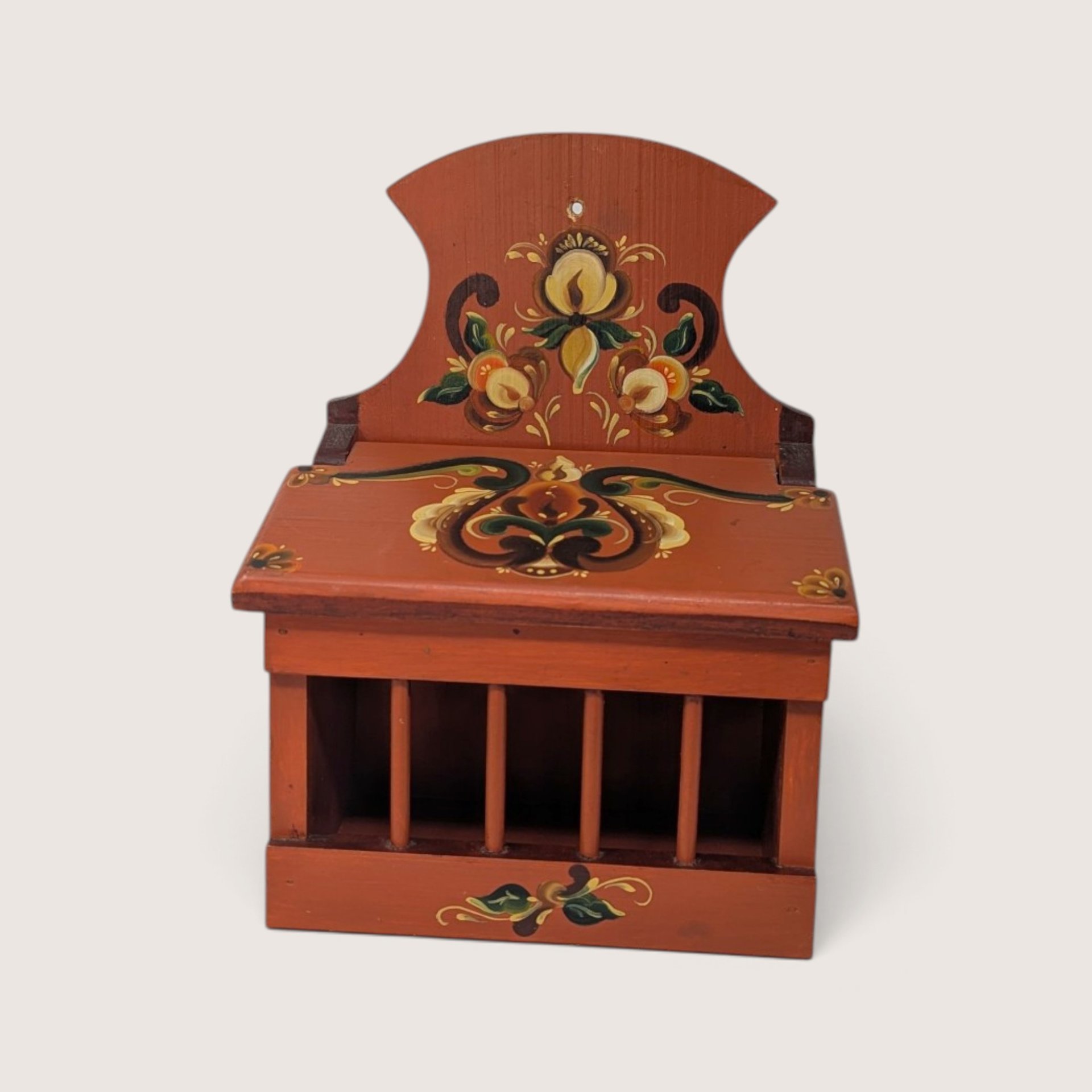 A vintage reddish-brown wooden onion box featuring traditional hand-painted floral folk art designs, a slatted front grill, a hinged lid, and a wall-mounting hole on the upper back panel against a neutral background.