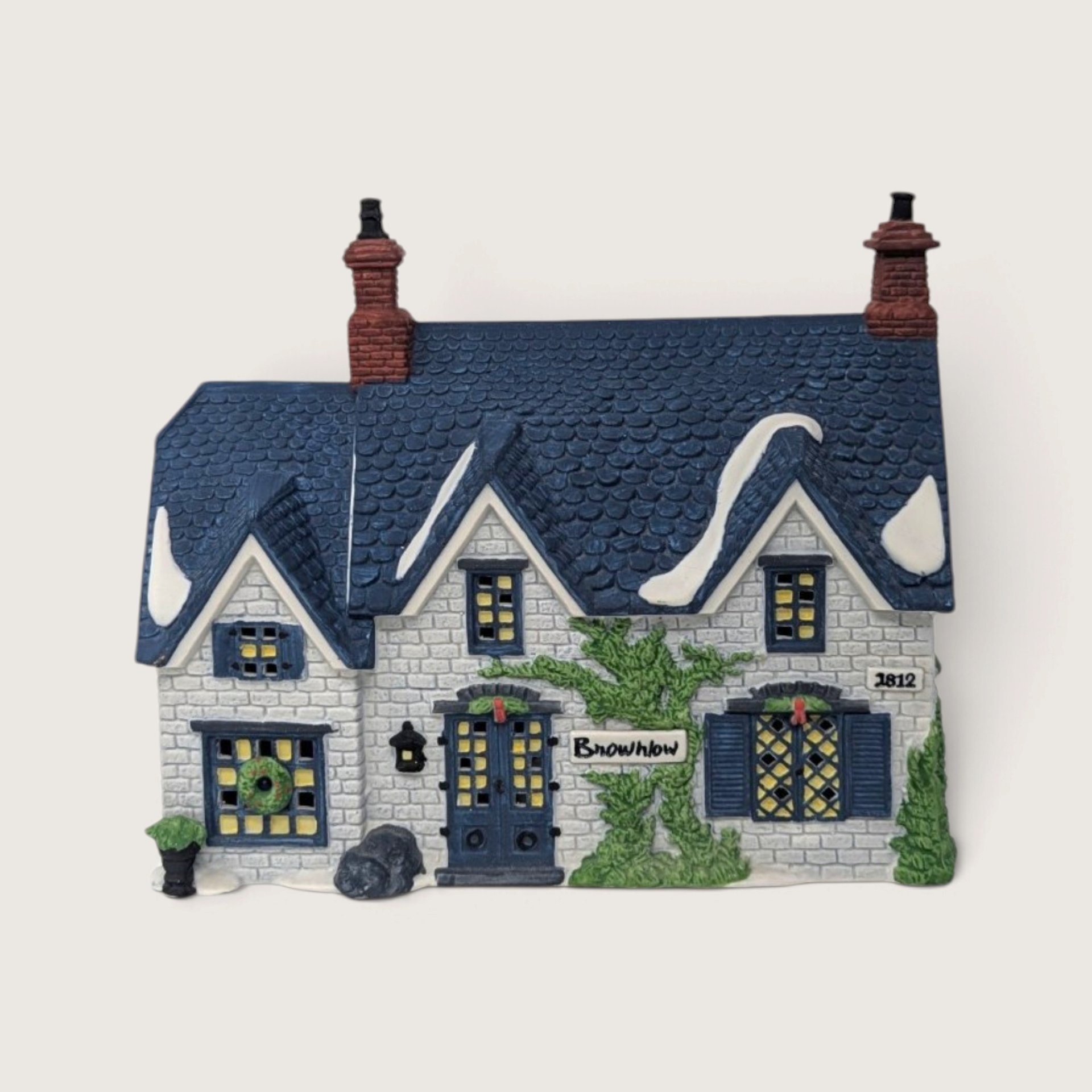 A vintage Department 56 Dickens Village Brownlow House building featuring a blue shingle roof with snow accents, white brick walls, and an ivy vine across the front.