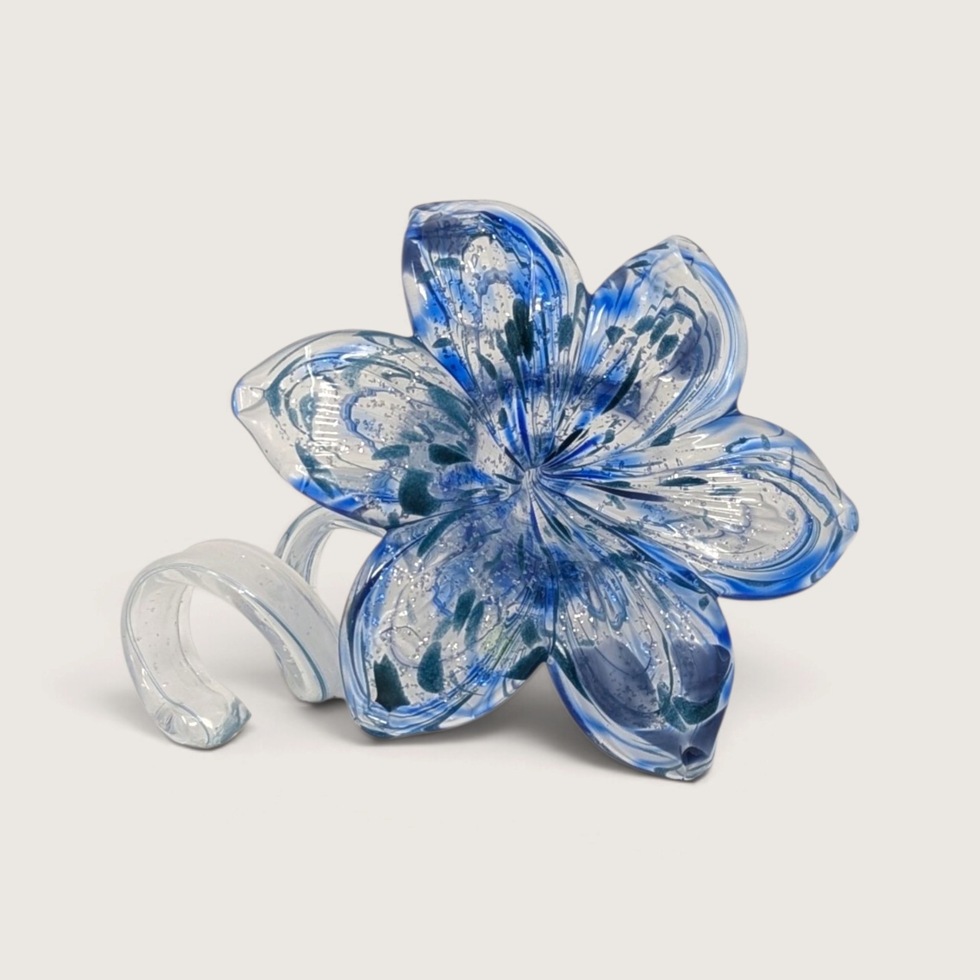A vintage blue and white art glass flower figurine with speckled details, a wide blossomed head, and a clear looped stem base.
