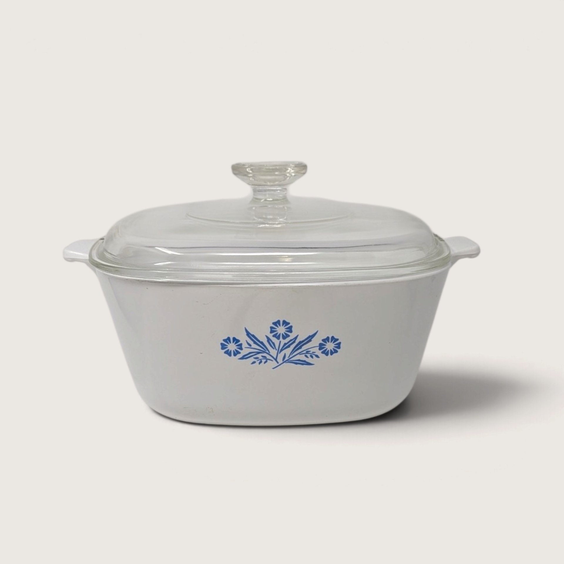 A vintage Corningware 2.5 quart square casserole dish in the blue cornflower pattern with a matching glass lid on a neutral background.