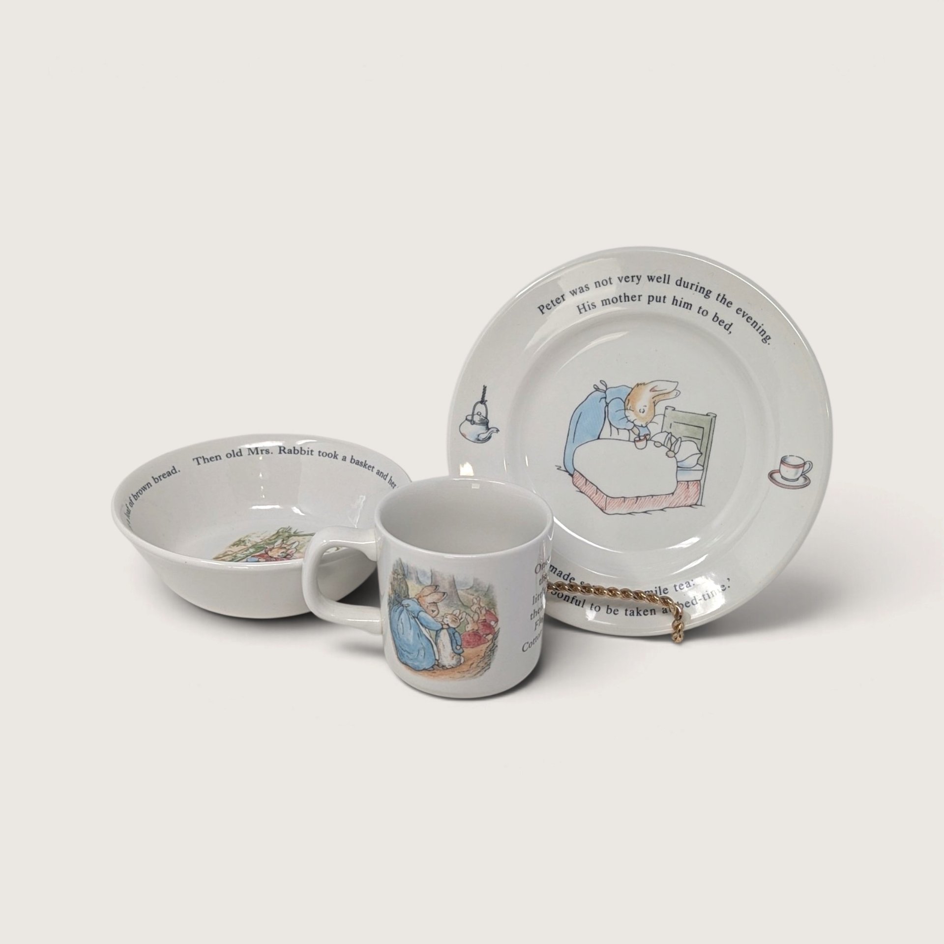 A vintage Wedgwood Peter Rabbit 3-piece child's dinner set including a decorated plate, a cereal bowl, and a mug featuring classic Beatrix Potter illustrations against a neutral background.