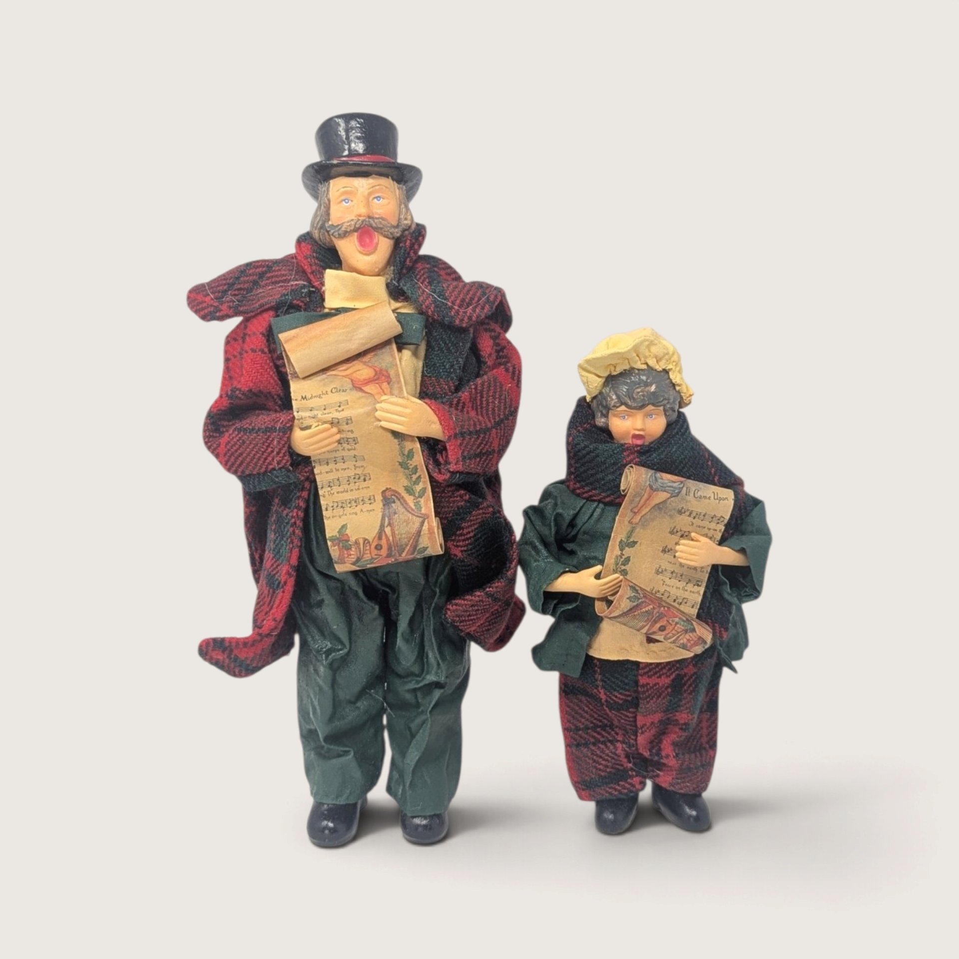 Vintage Santa's World Kurt Adler Victorian caroler man and child figurines in red and green plaid outfits holding sheet music.   