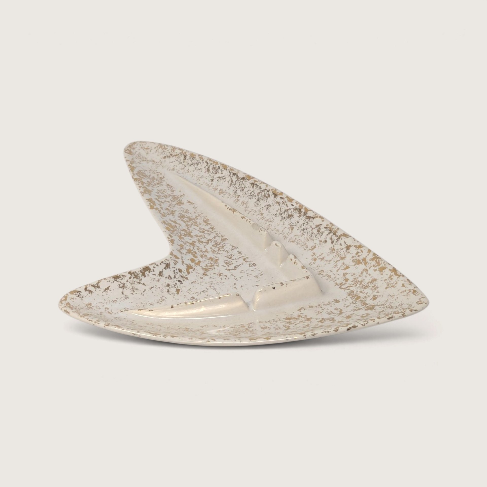 Vintage 1950s Shawnee pottery atomic boomerang-shaped ashtray in off-white glaze with metallic gold splatter.   