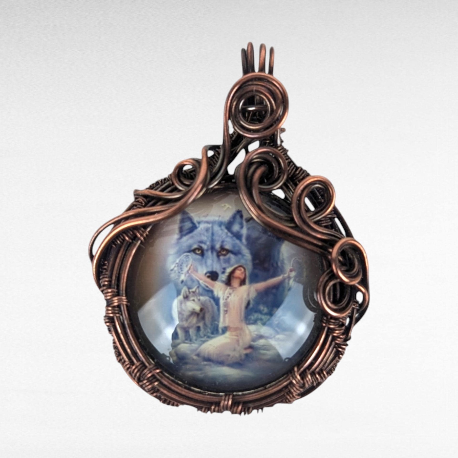 Copper wire wrapped picture cabochon depicting a female with our stretched arms with wolves behind her
