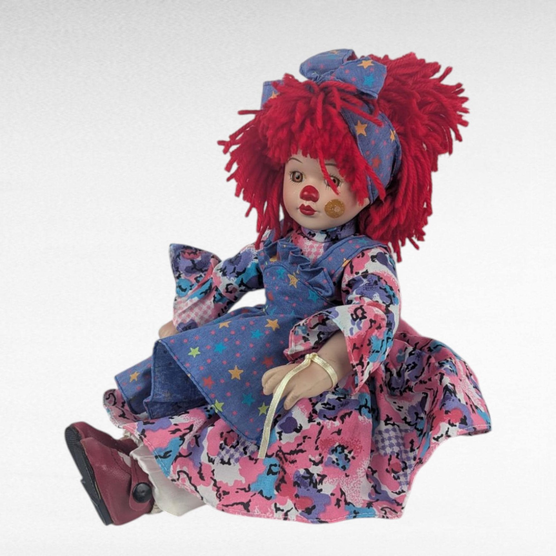 Vintage Porcelain Clown Doll, 9" Sitting Jester with Red Yarn Hair, Collectible Shelf Sitter Doll in Floral Star Dress