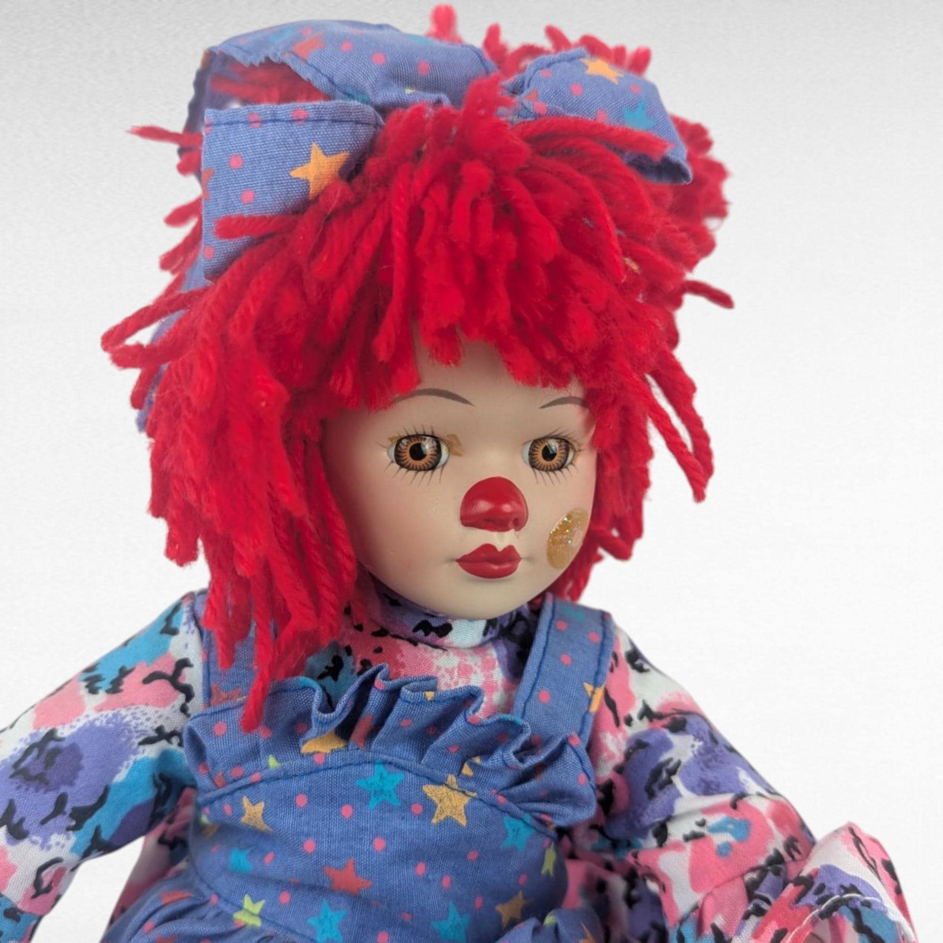 Vintage Porcelain Clown Doll, 9" Sitting Jester with Red Yarn Hair, Collectible Shelf Sitter Doll in Floral Star Dress