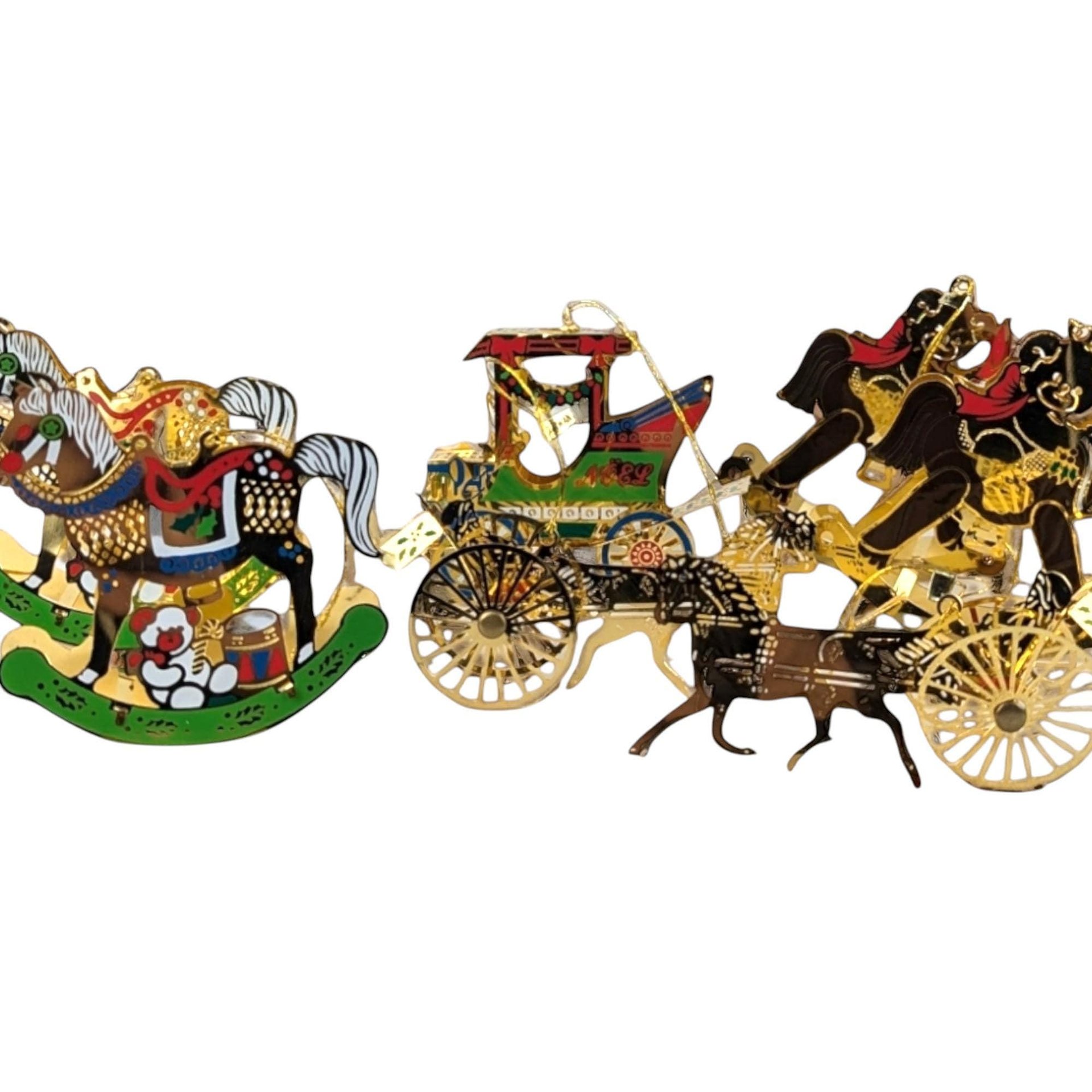 A horizontal view of a set of seven vintage brass-colored metal Christmas ornaments. The collection features a variety of classic equestrian and holiday designs, including several intricate rocking horses, a detailed horse-drawn buggy with a carriage, and other ornate filigree shapes. Each piece has a warm, golden metallic finish with delicate cutout details.