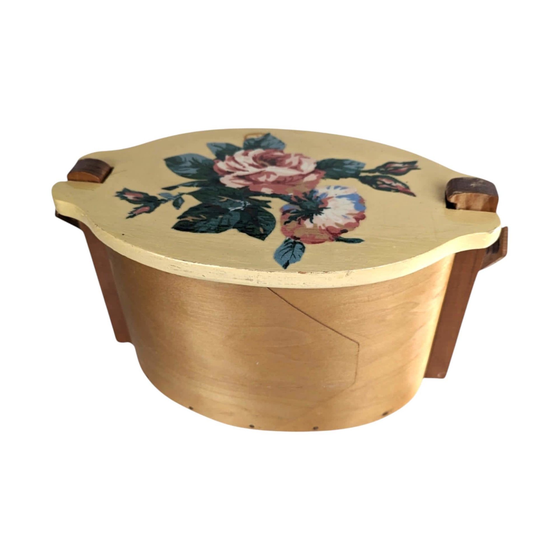 A vintage wooden woven basket with a hinged lid featuring a hand-painted floral design of a pink rose and blue flowers, with a stationary arched wood handle.