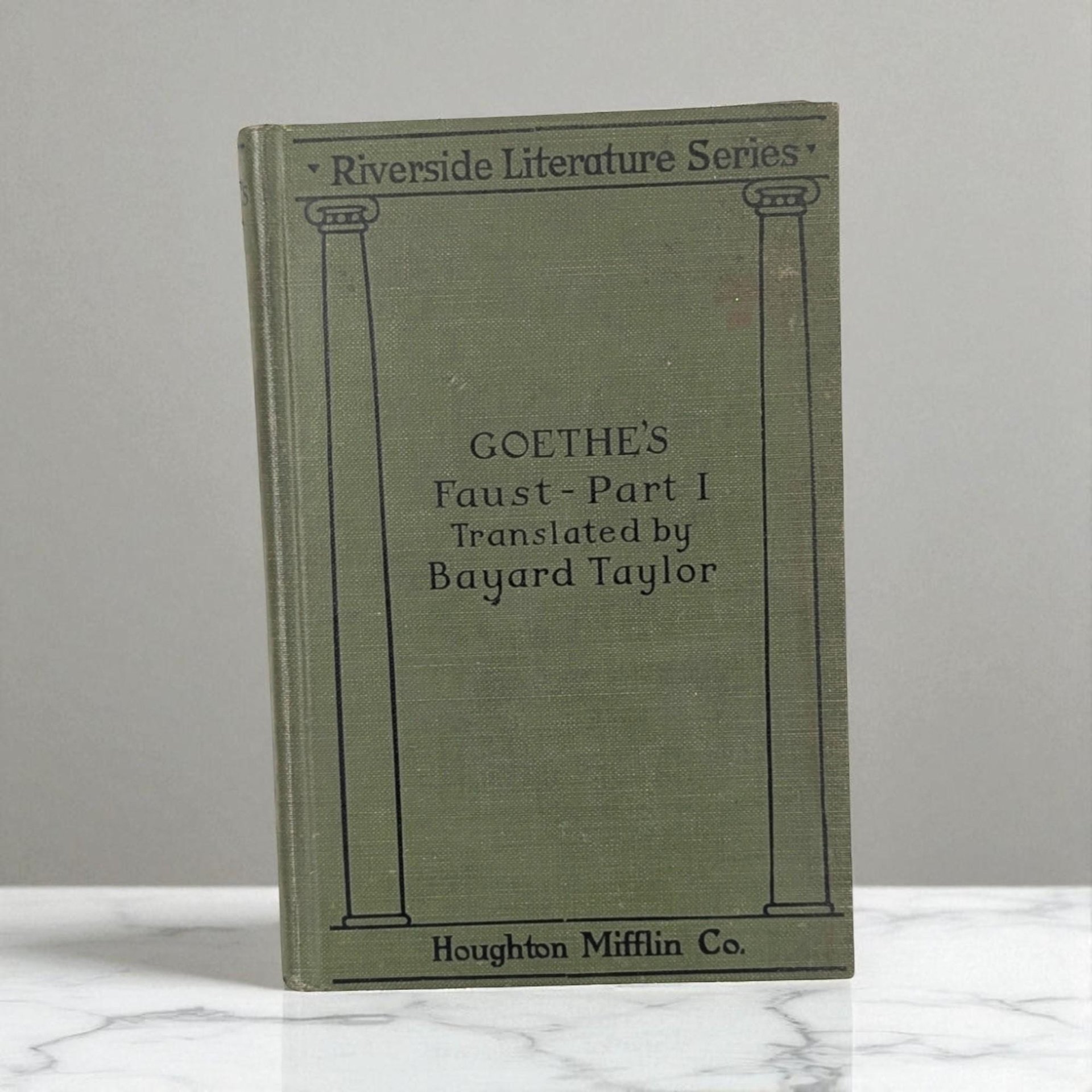 An antique olive green hardcover book titled Goethe's Faust. The binding features a smooth matte texture with dark embossed lettering and a simple vertical line design. The silhouette is rectangular with sharp, well-preserved corners.