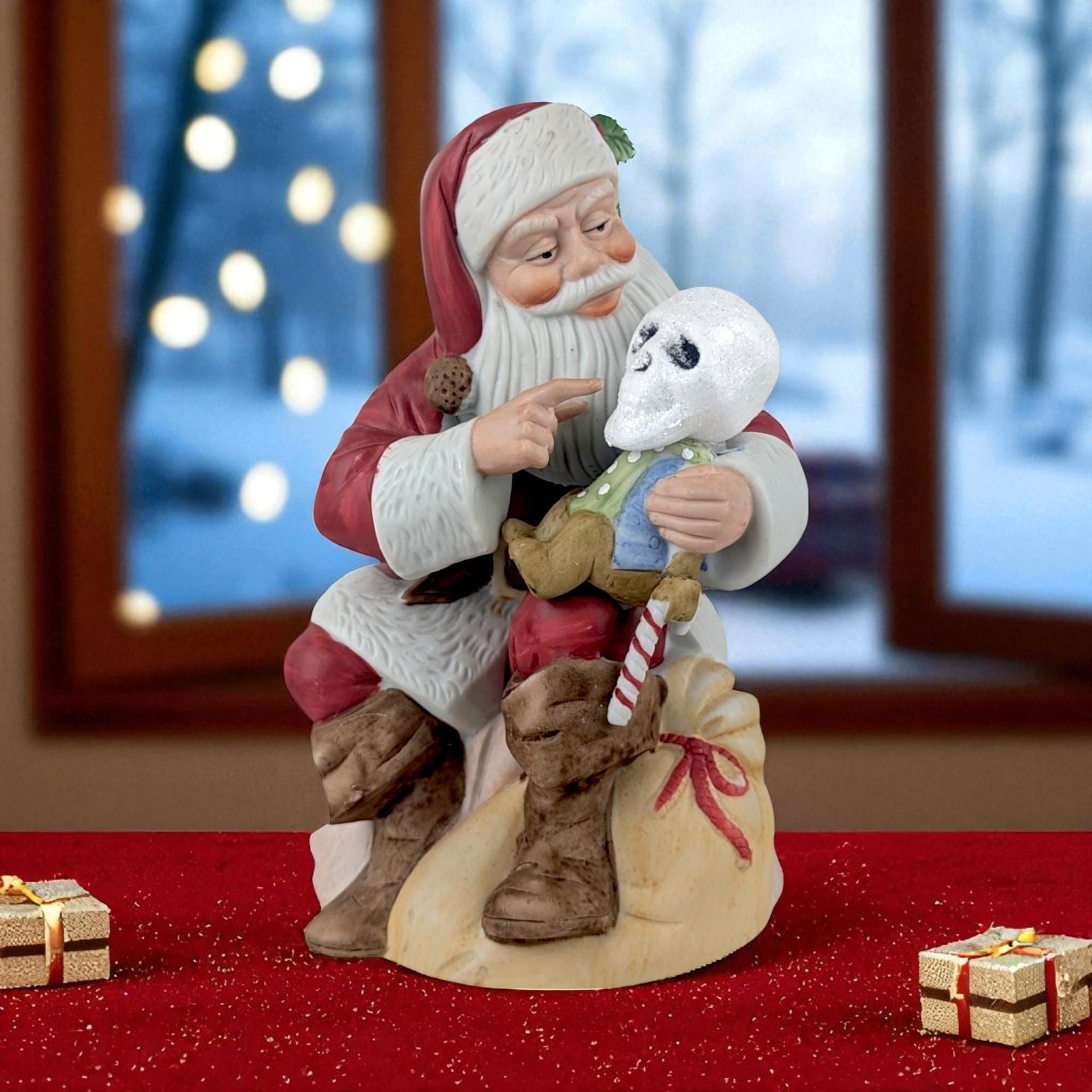 A hand-painted ceramic Santa figurine seated on a burlap sack, cradling a small skeleton figure dressed in a blue and green outfit. Santa features a matte red suit, white textured beard, and brown boots, pointing his finger toward the skeleton's face.