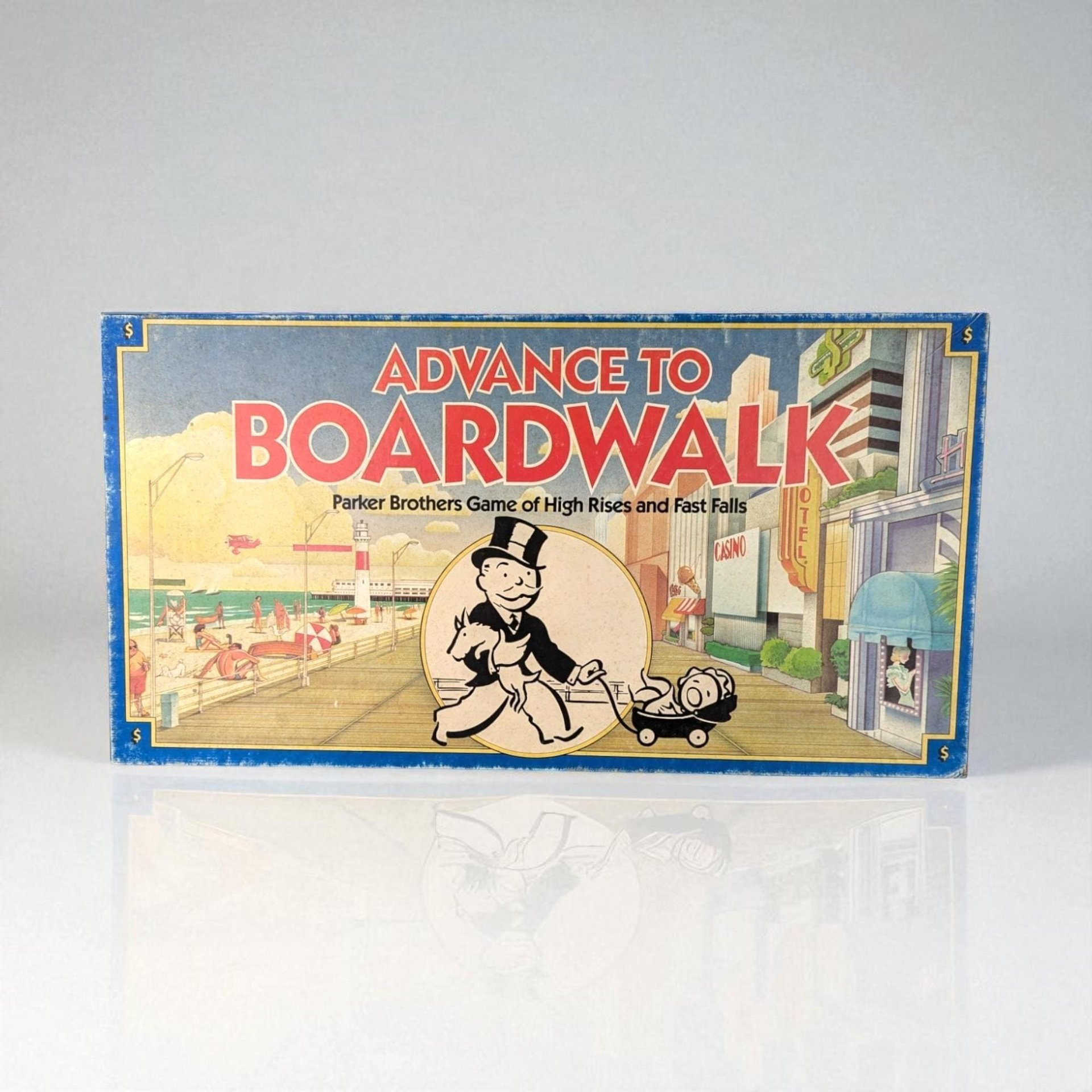 Vintage board game box for Advance to Boardwalk. The cover features a matte paper finish with a blue border and vibrant illustrations of a beachside boardwalk. Mr. Monopoly is centered in a circular frame, wearing a tuxedo and top hat.