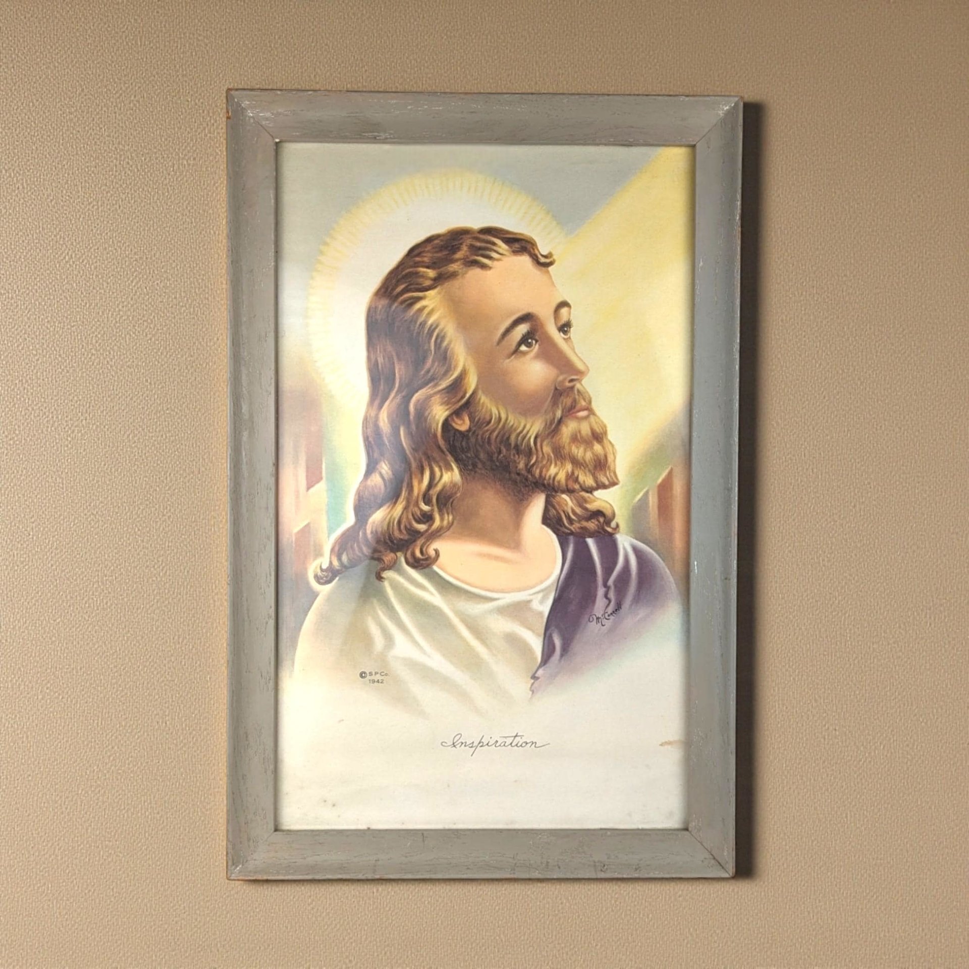 A vertical lithograph of Jesus Christ titled Inspiration in a weathered gray wood frame. The portrait features warm yellow light, a soft halo, and a purple robe against a cream background. The texture of the aged paper and wood grain is visible.
