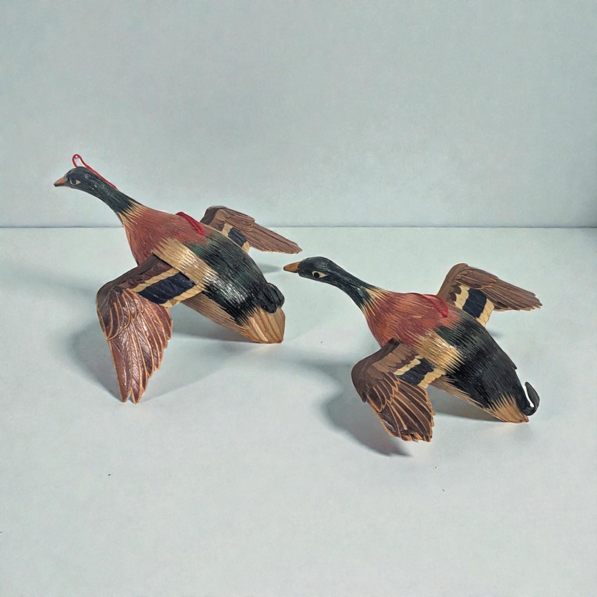 Set of small hand-painted wooden duck ornaments. Each features a traditional decoy silhouette with a green head, yellow bill, and brown feathered detailing on the body.