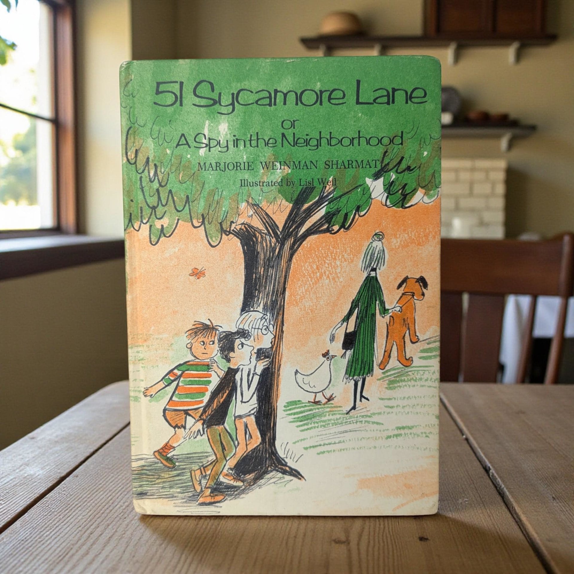 A slim hardcover book with a green and white illustrated cover showing children observing a house. The artwork is in a whimsical, mid-century sketch style with bold black outlines and limited color.