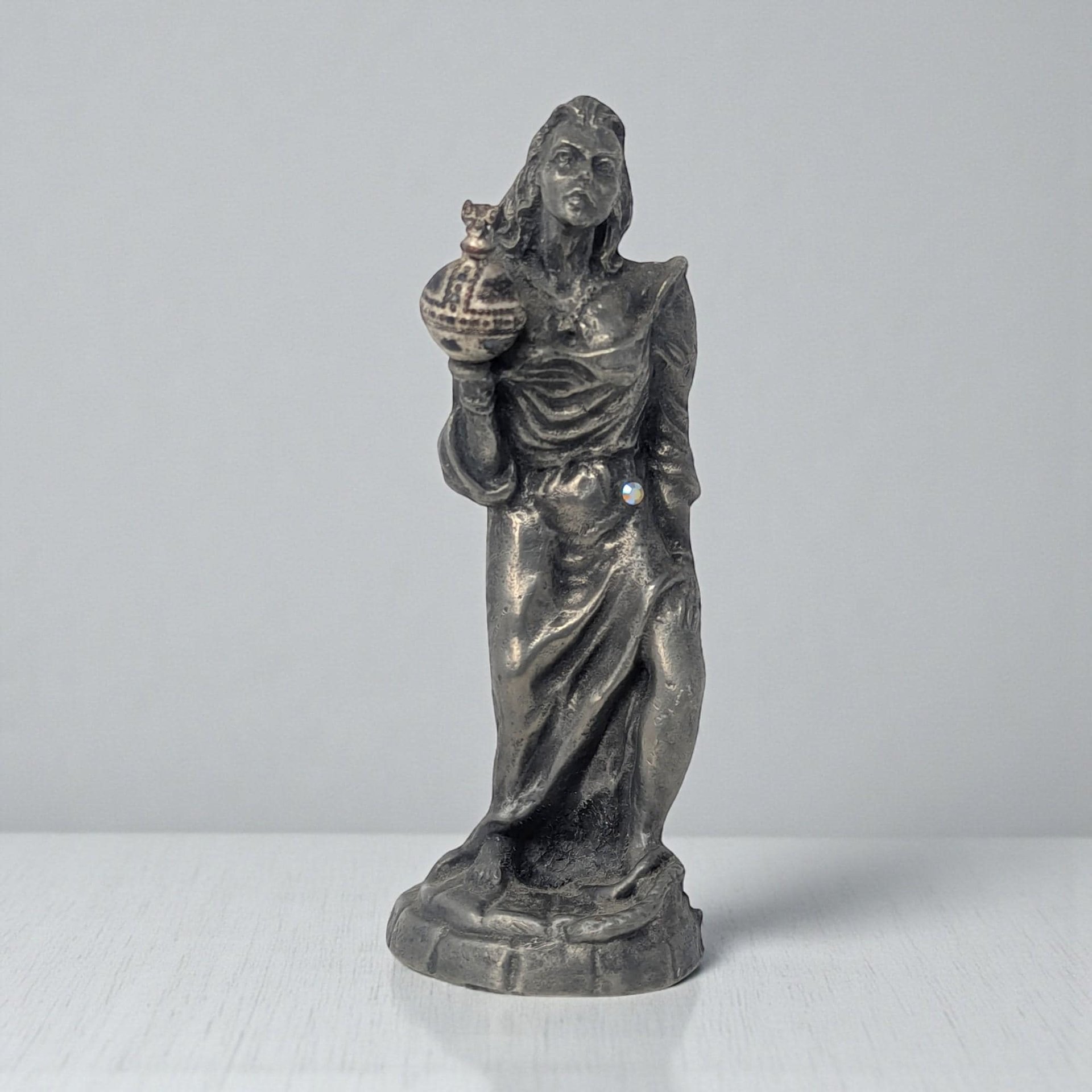 A solid pewter figurine of a slender female form standing atop a small integrated base. The metal has a soft, satin-like luster and a smooth, flowing silhouette that emphasizes graceful lines.