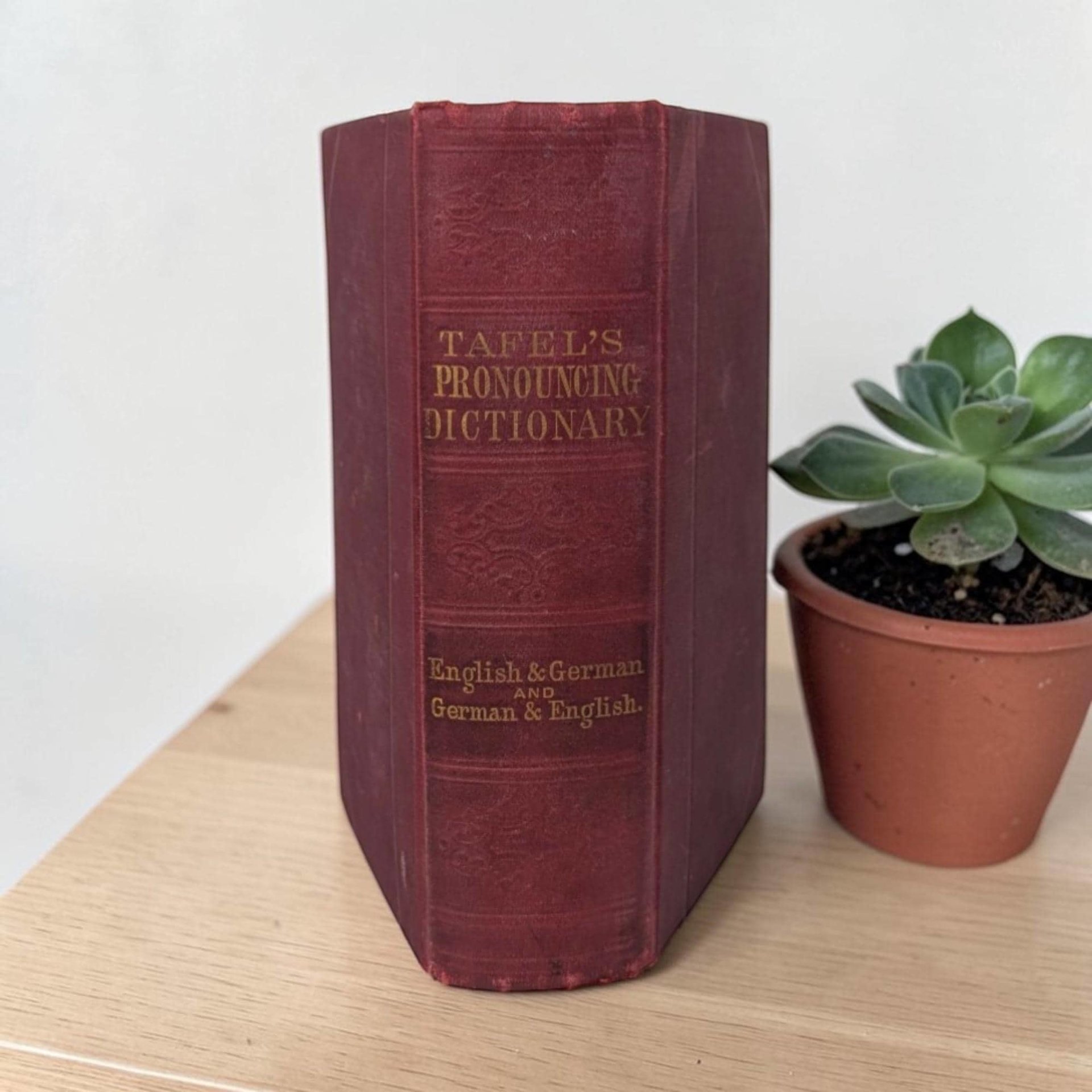 A small, dark hardcover book with a weathered and textured surface. The cover is a deep, faded black or charcoal color. The title and some decorative detailing are visible as faint, recessed impressions on the front.