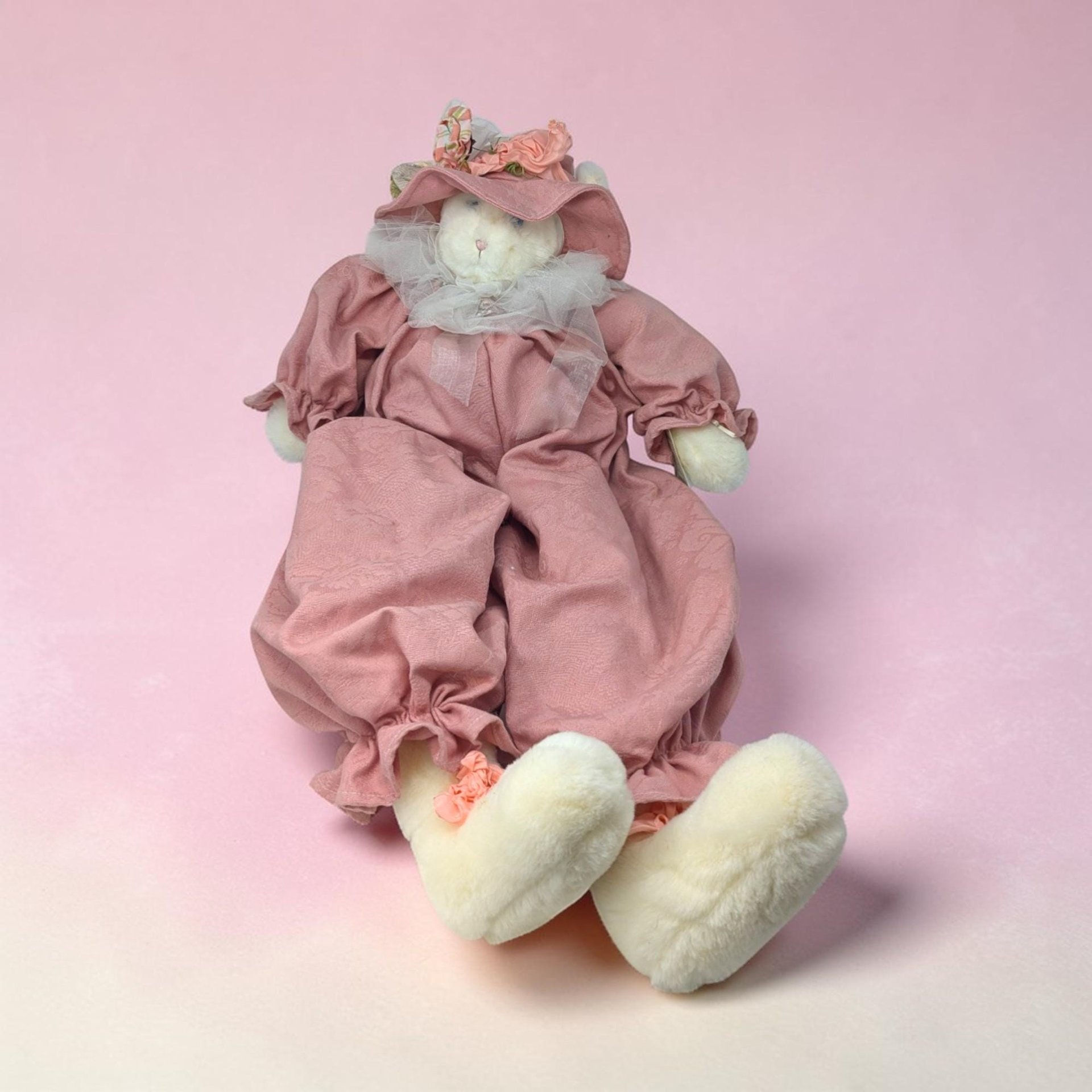 A large cream-colored handmade plush cat with exceptionally long, slender limbs and a hand-stitched face. The cat is shown in a seated position with a weighted base and wears a vintage-style fabric outfit with a lace collar.