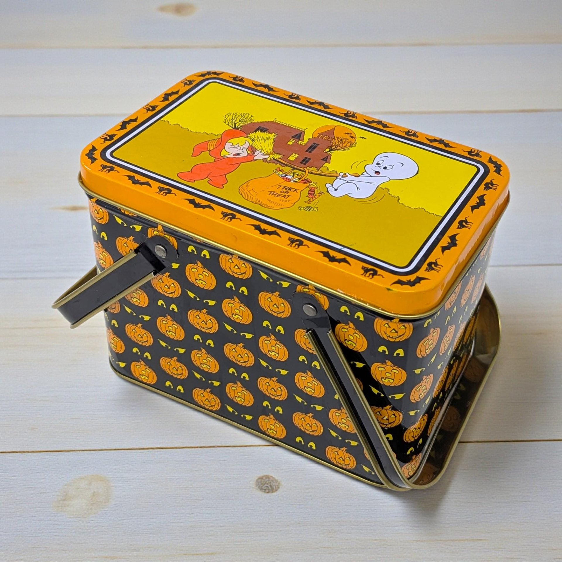 A rectangular tin basket with a metal swing handle. The exterior features vibrant graphics of Casper the Friendly Ghost against a night-sky background. It shows a small scrape on the side and minor indentations consistent with vintage use.
