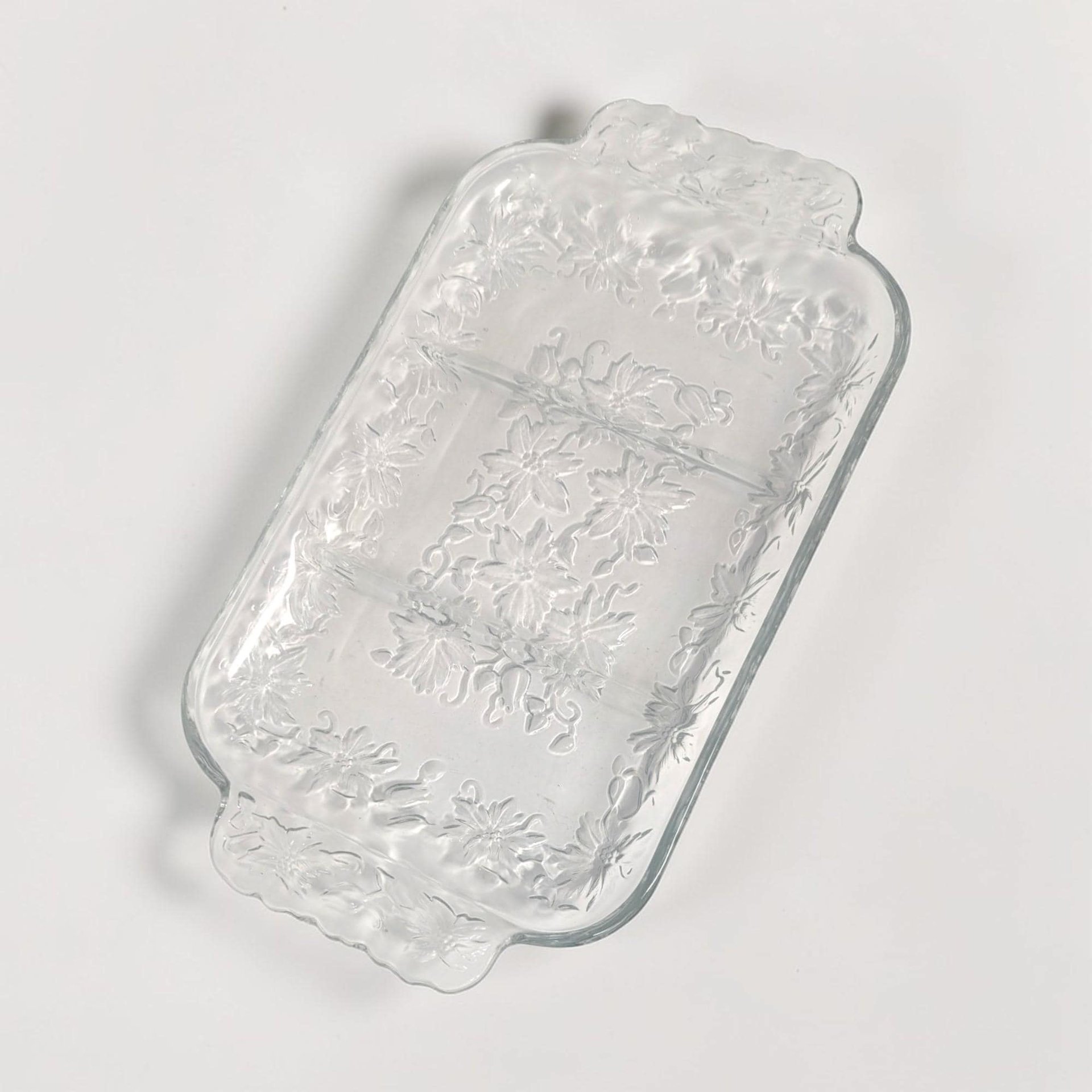A rectangular clear glass dish featuring three divided sections and integrated handles at each end. The glass is embossed with a delicate frosted floral and vine pattern along the border and center.