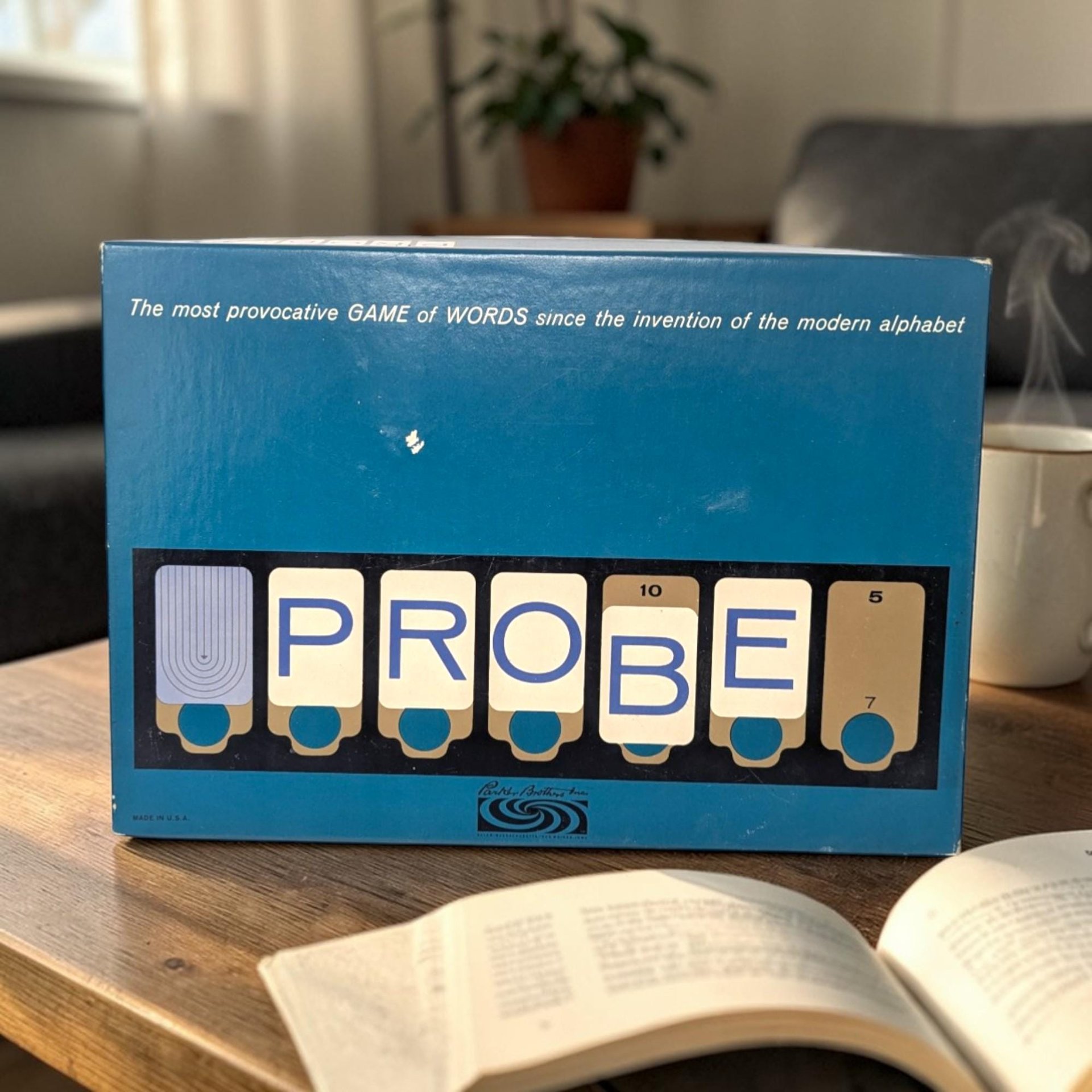 A blue rectangular game box sitting on a wooden table. The word "PROBE" is displayed across the bottom in stylized white cards with blue lettering. A small white scuff is visible on the center of the blue background.